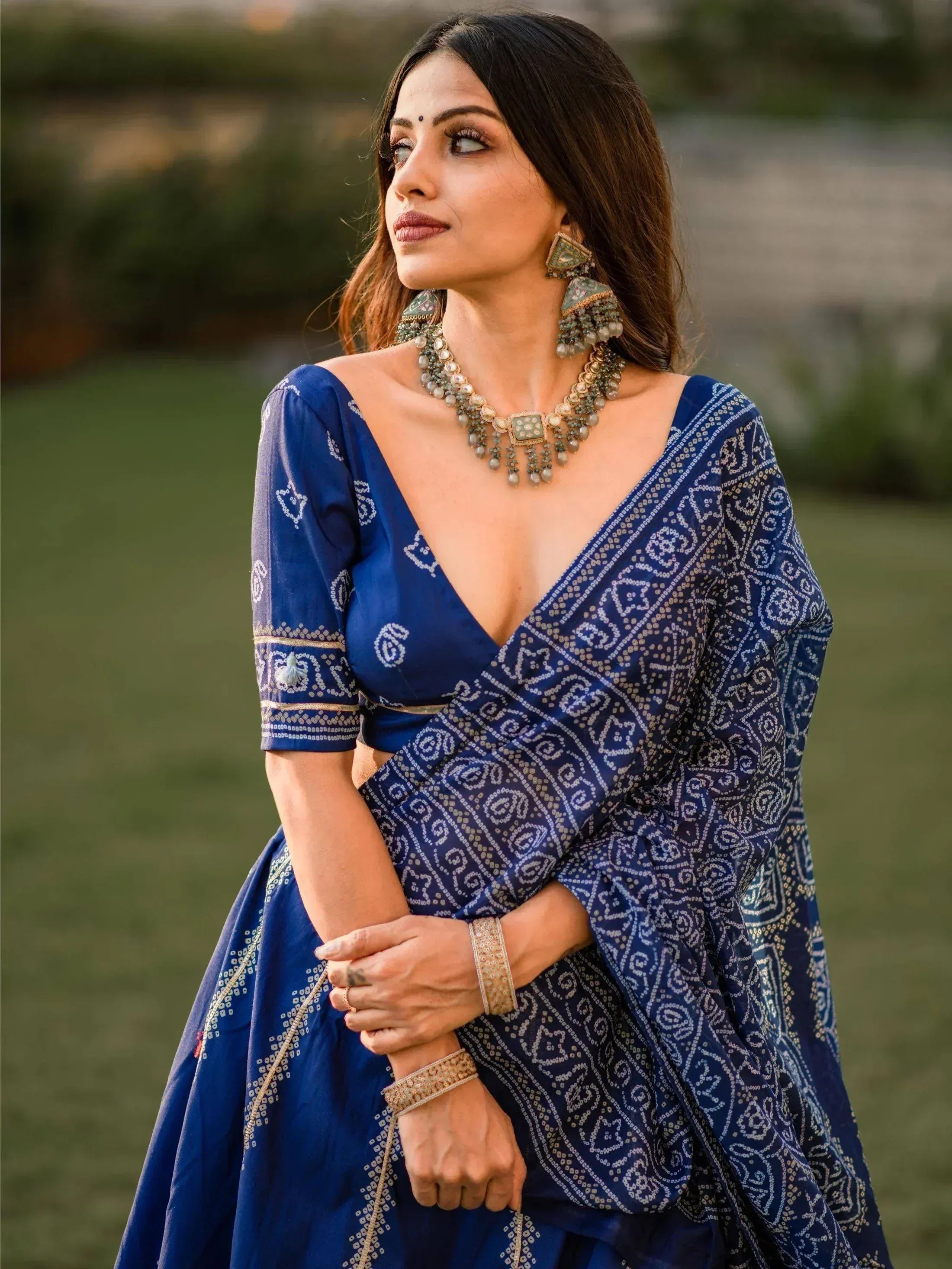 Woman in blue printed lehenga choli with ethnic jewelry, perfect for Indian weddings and festive occasions.