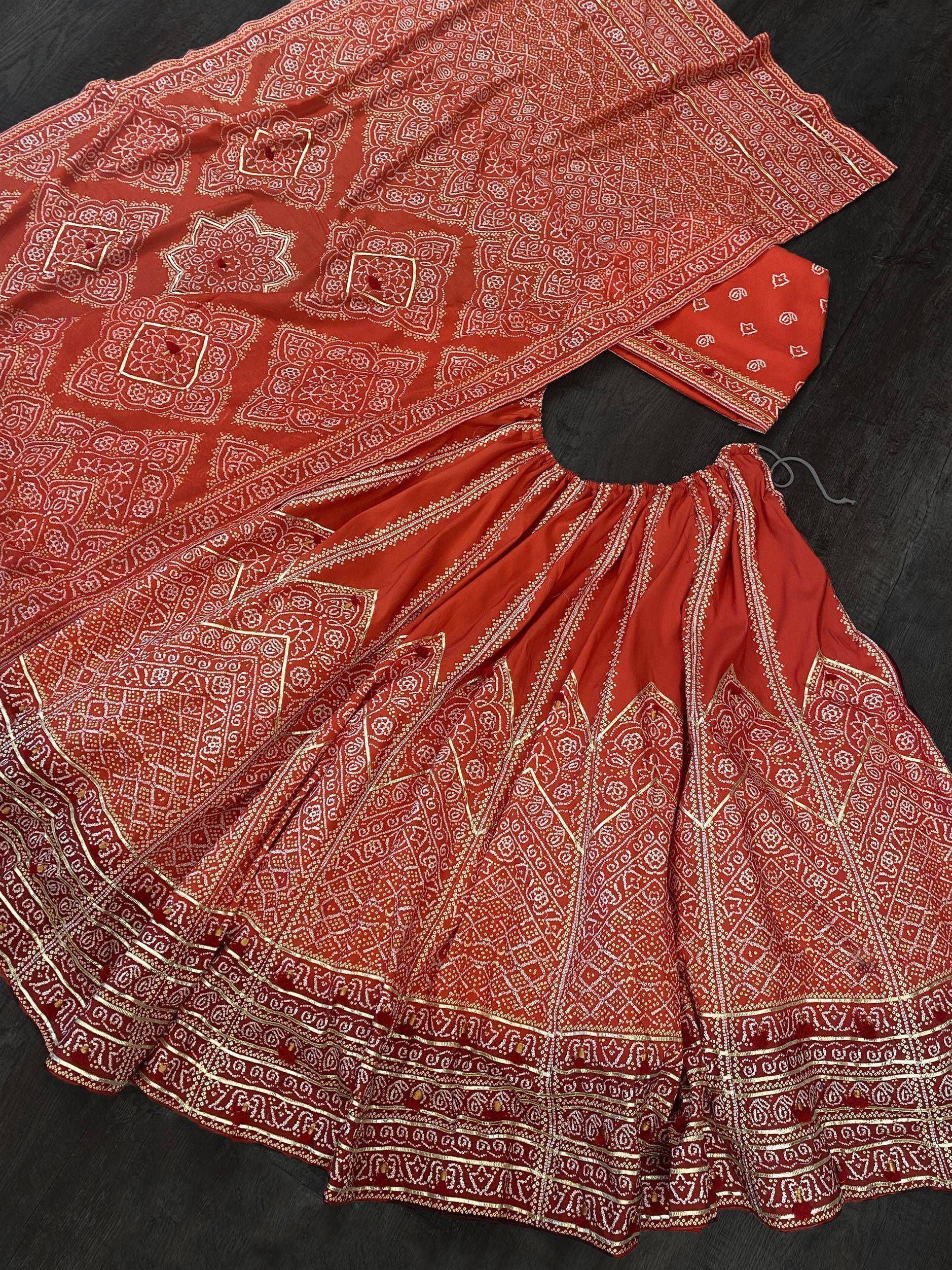 Red ethnic lehenga choli with intricate white and gold bandhani print, perfect for Indian weddings and festivals