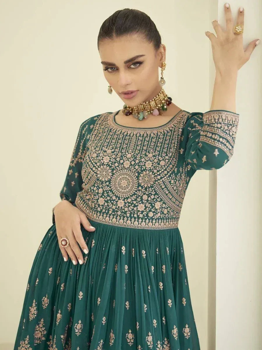 Woman wearing a green embroidered ethnic gown with statement jewelry, posing indoors