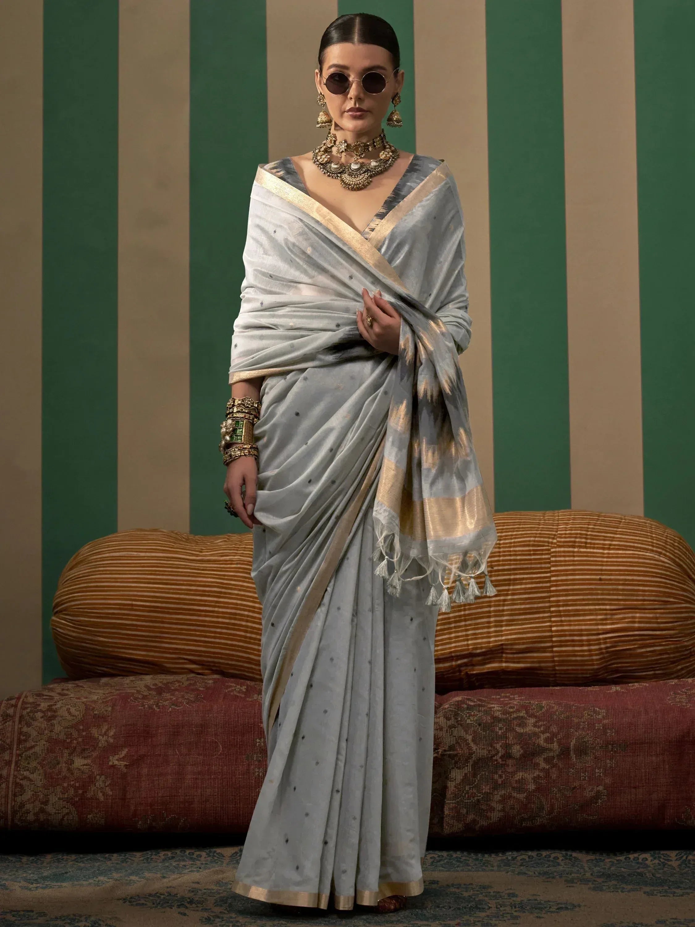 Elegant grey silk saree with gold border and tassels, paired with traditional jewelry for Indian ethnic wear.