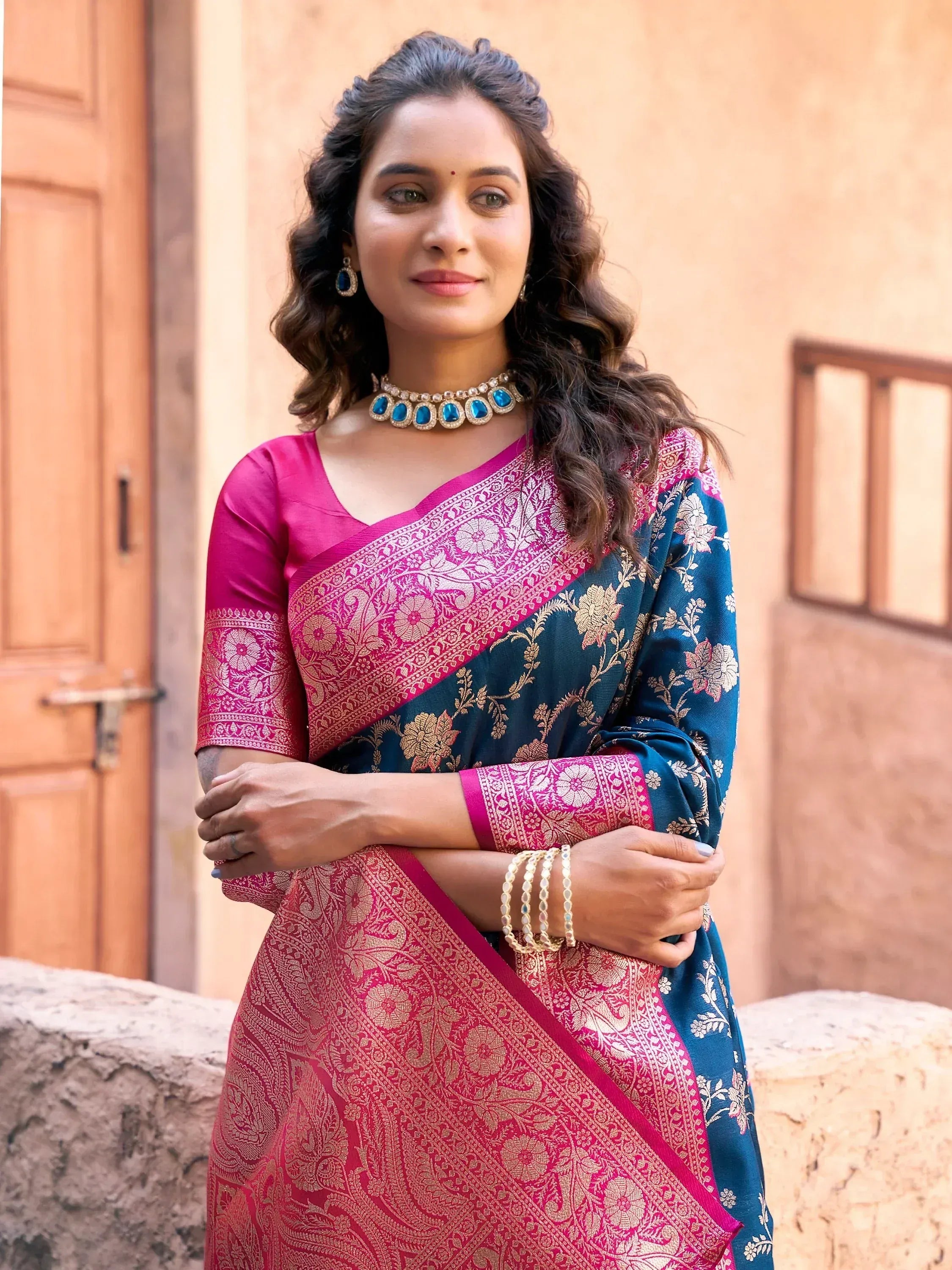 Woman in elegant pink and teal designer saree with gold floral embroidery, perfect for Indian ethnic occasions.