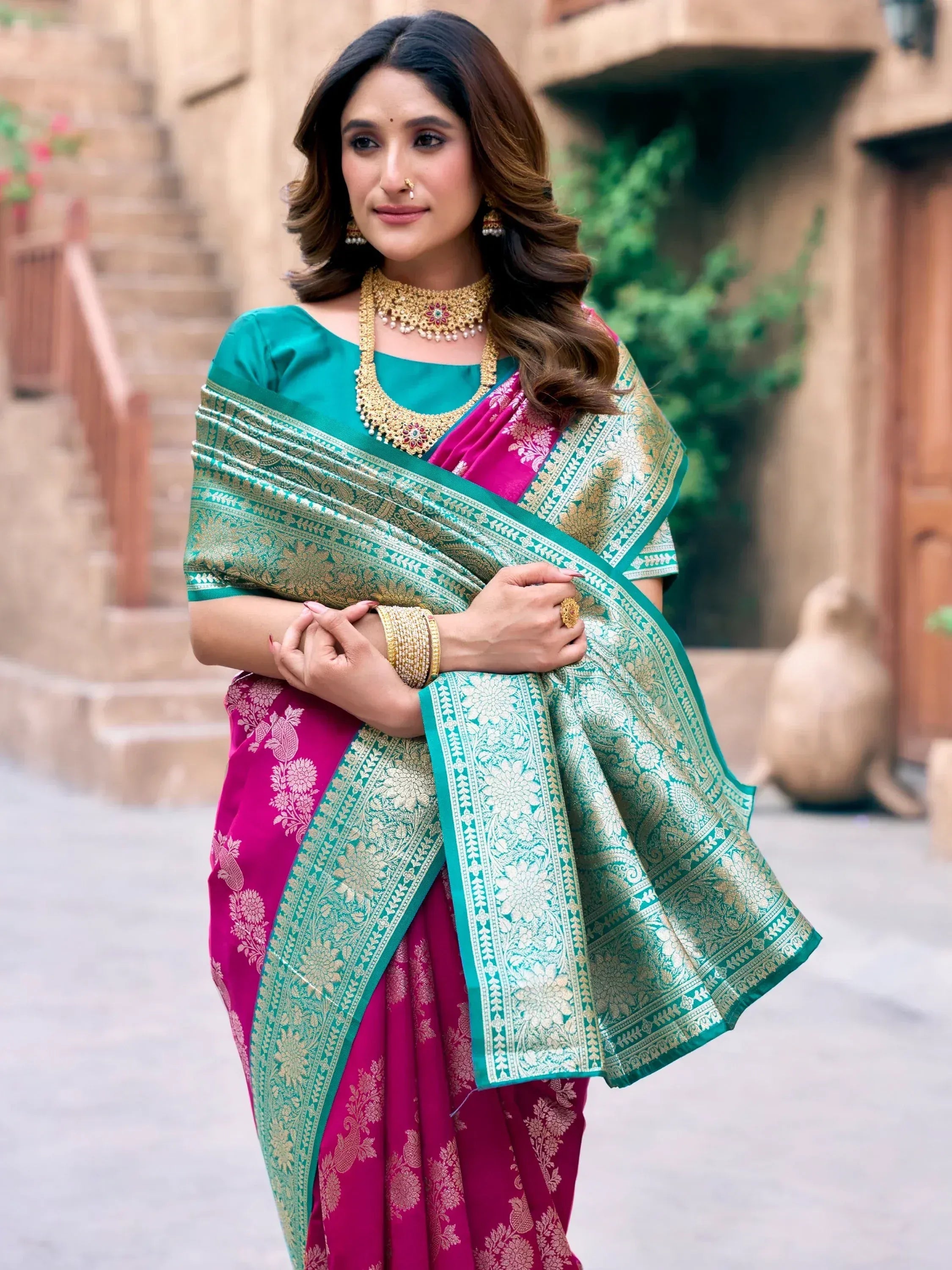 Woman in vibrant pink and green designer saree with gold embroidery, traditional Indian ethnic wear