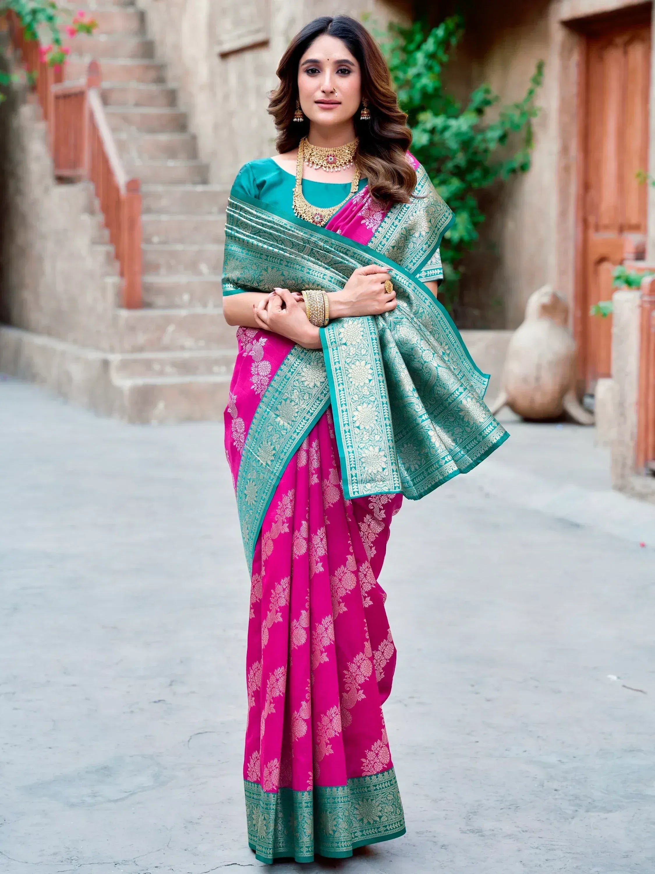 Woman in vibrant pink and teal designer saree with gold embroidery, perfect for Indian ethnic wear occasions