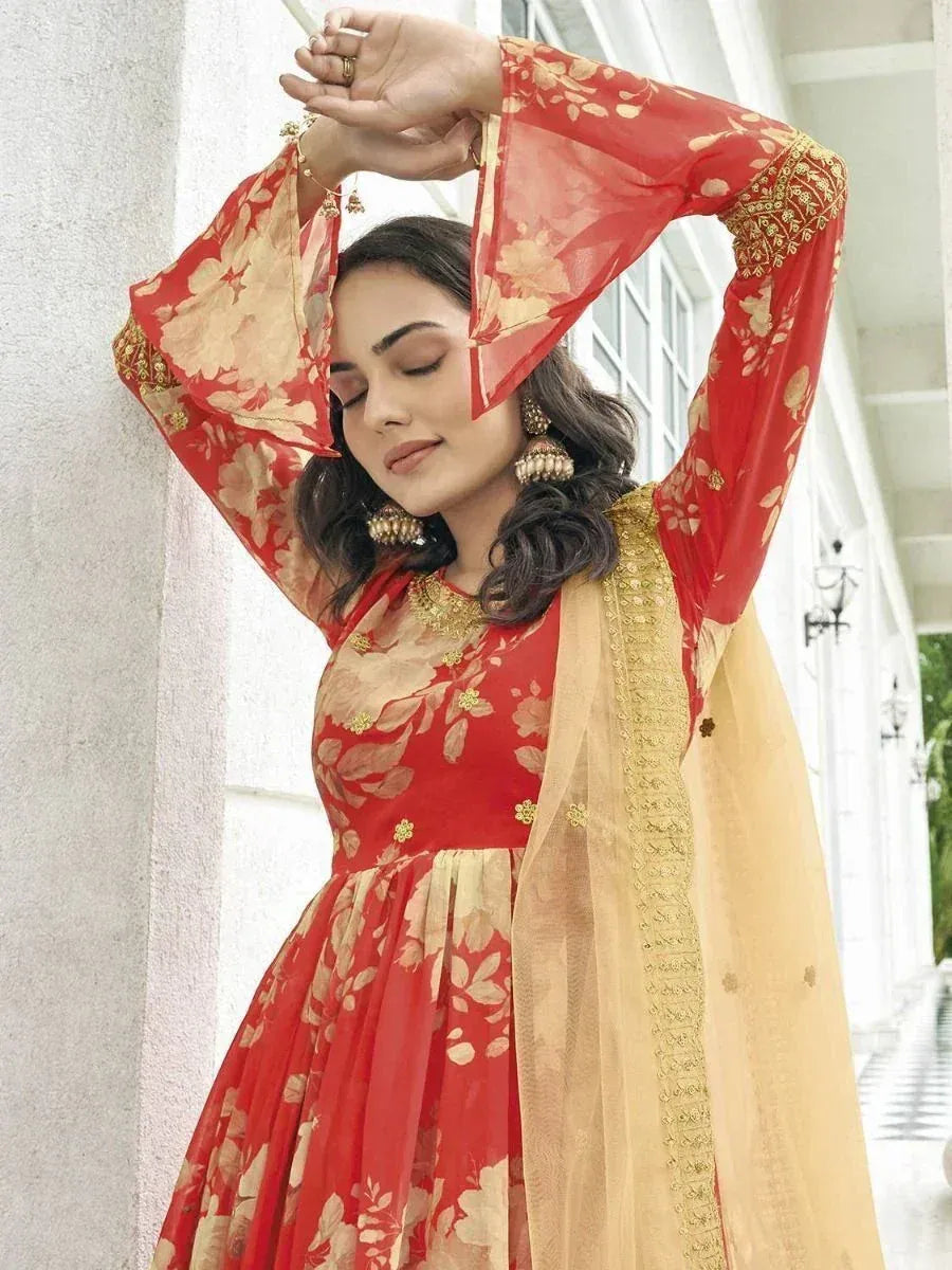 Woman in red and gold floral ethnic gown with flared sleeves and beige dupatta