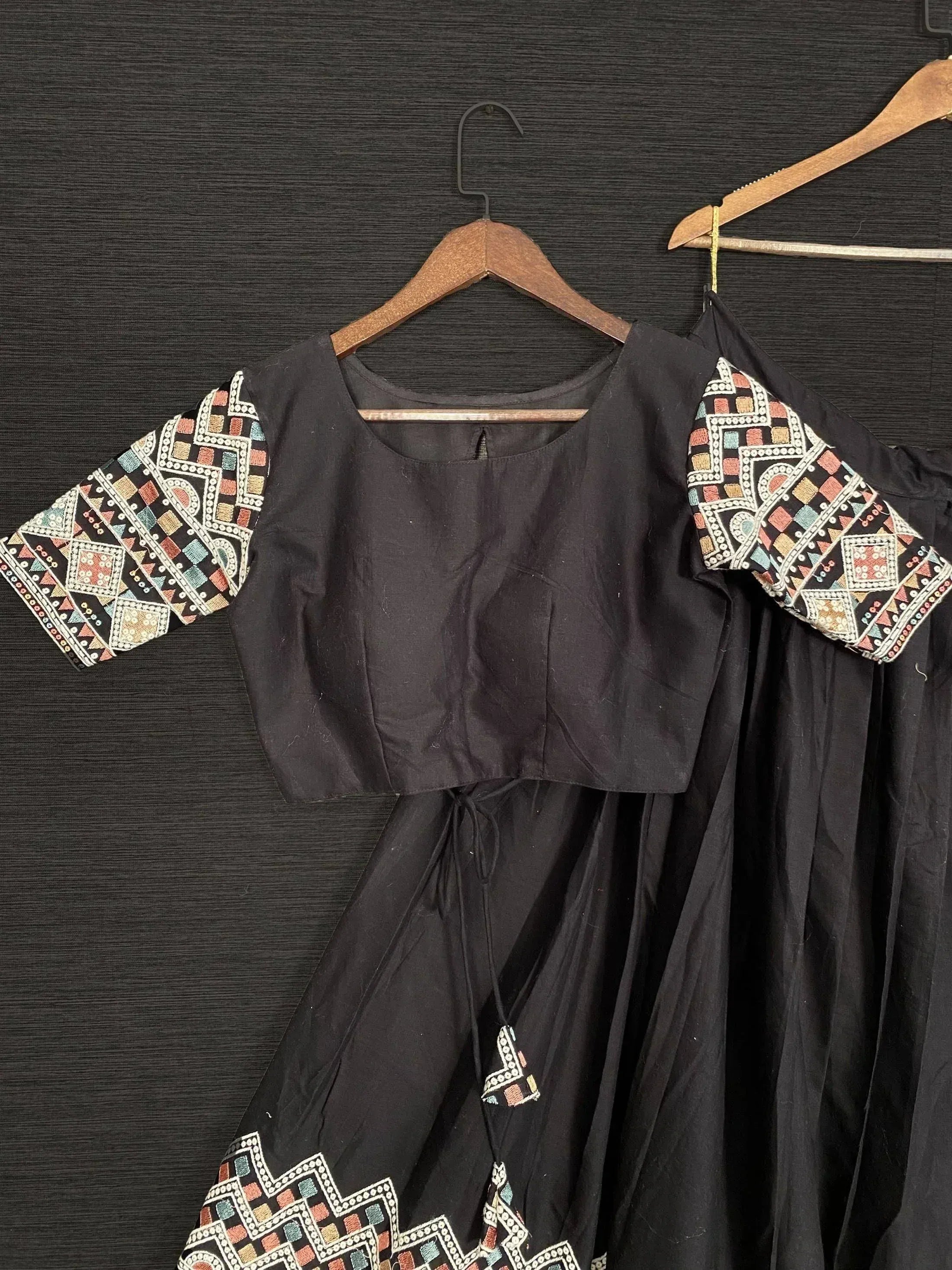 Black ethnic gown with colorful geometric embroidery on sleeves and hem, perfect for Indian festive wear.