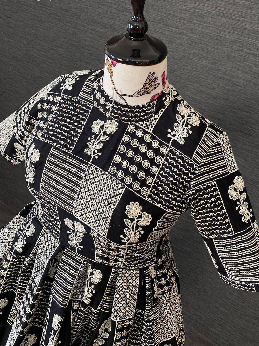 Black and white embroidered ethnic gown with floral and geometric patterns, displayed on mannequin