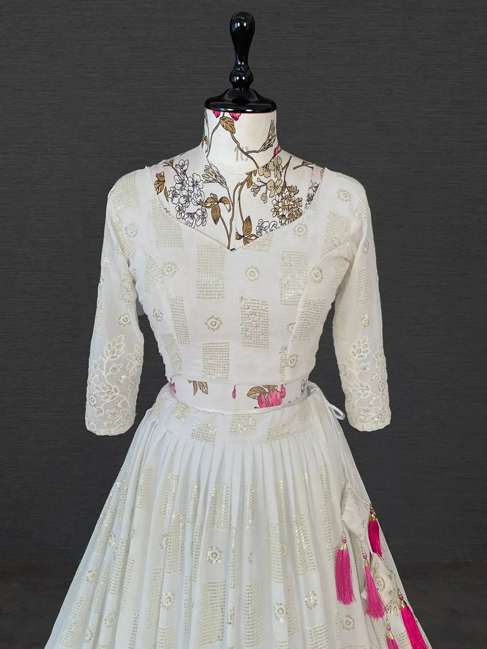 White floral embroidered ethnic gown with pink tassels, perfect for Indian celebrations and festive occasions.