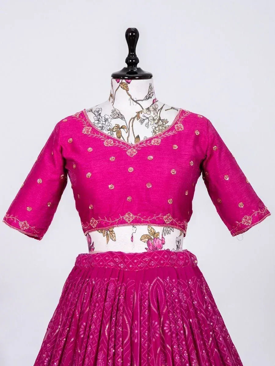Fuchsia pink embroidered lehenga choli with floral motifs and gold detailing, displayed on mannequin