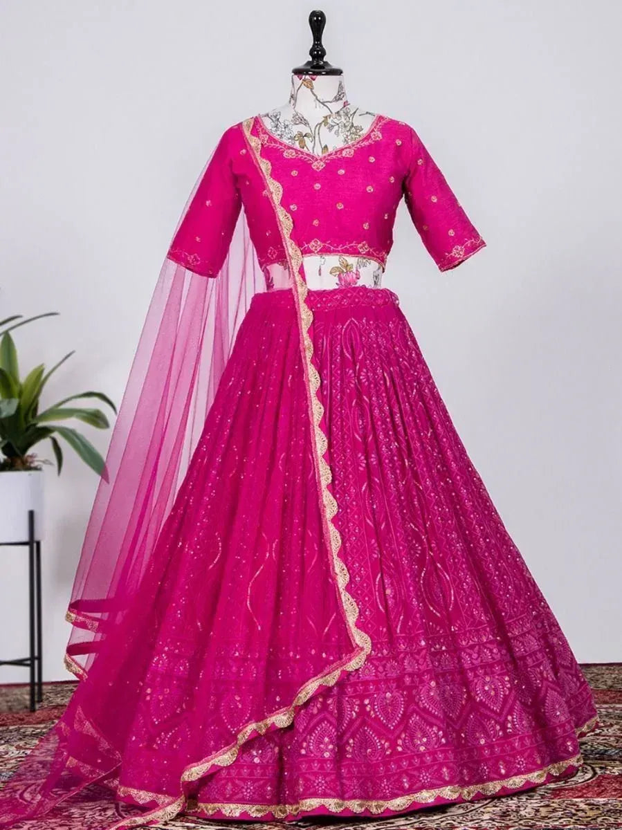Fuchsia pink designer lehenga choli with gold embroidery and sheer dupatta, perfect for Indian weddings and festive occasions.