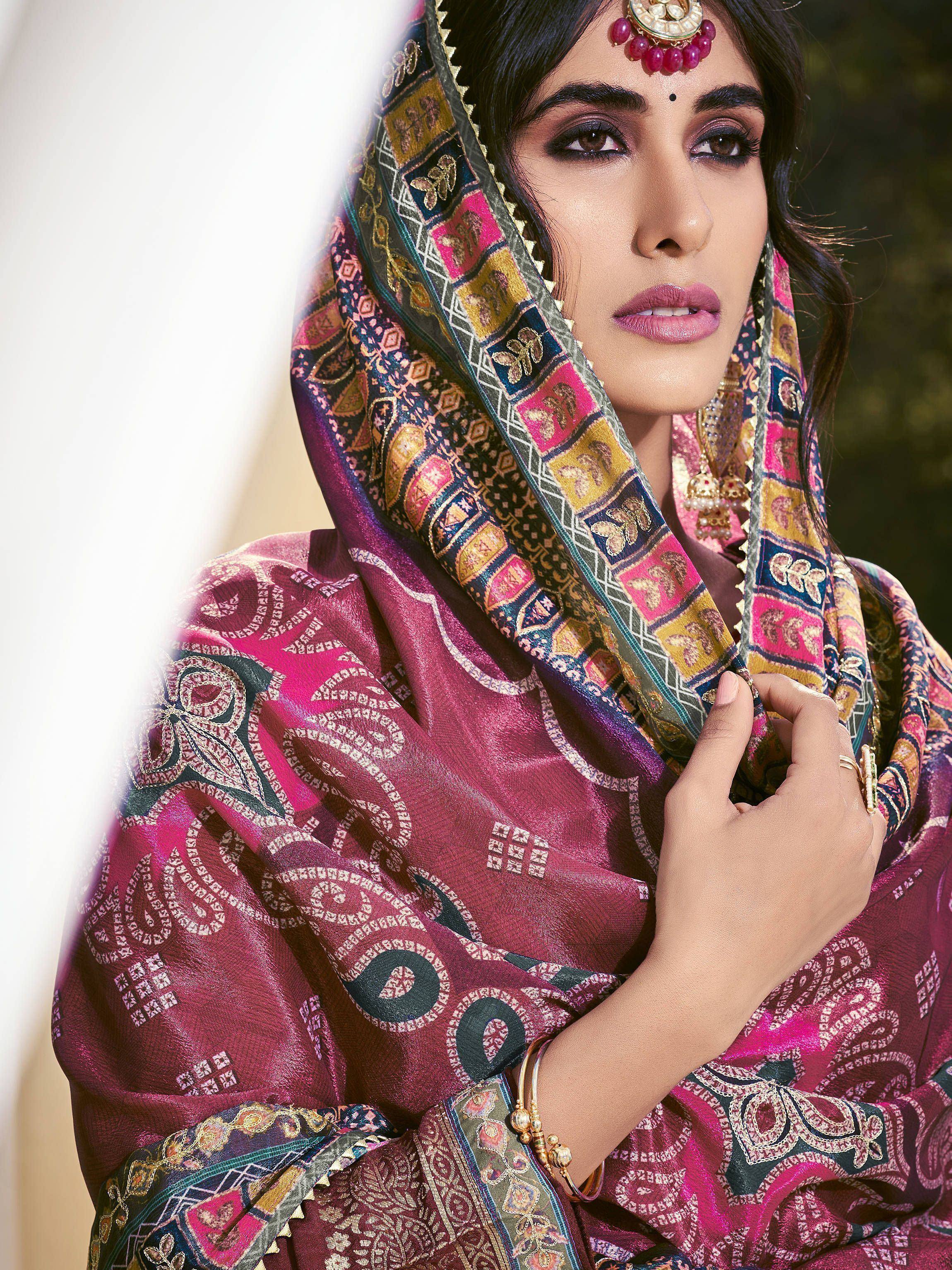 Woman in vibrant Indian ethnic wear with intricate paisley dupatta and traditional jewelry