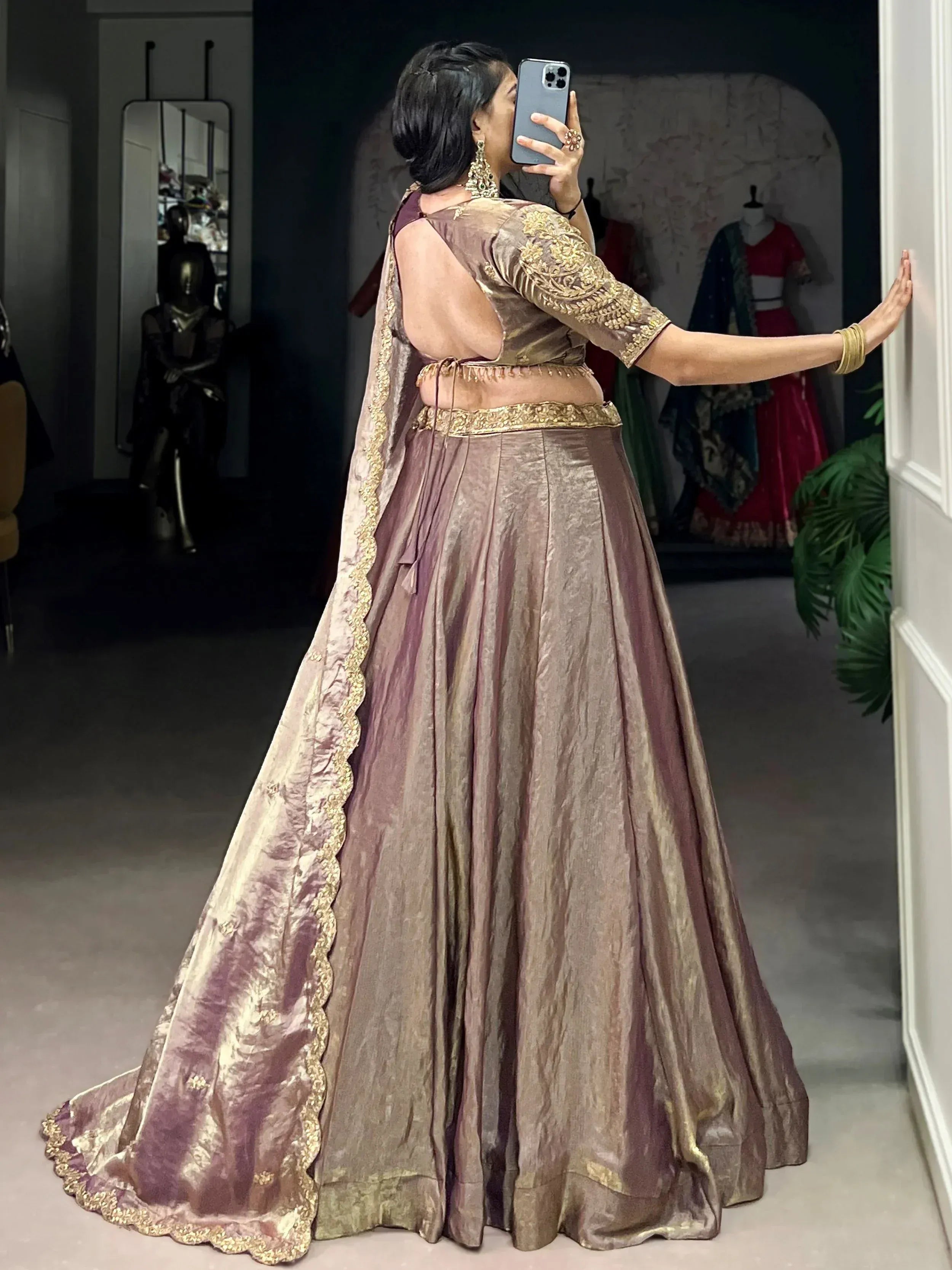 Woman taking mirror selfie in elegant mauve lehenga choli with gold embroidery, perfect for Indian ethnic wear occasions.