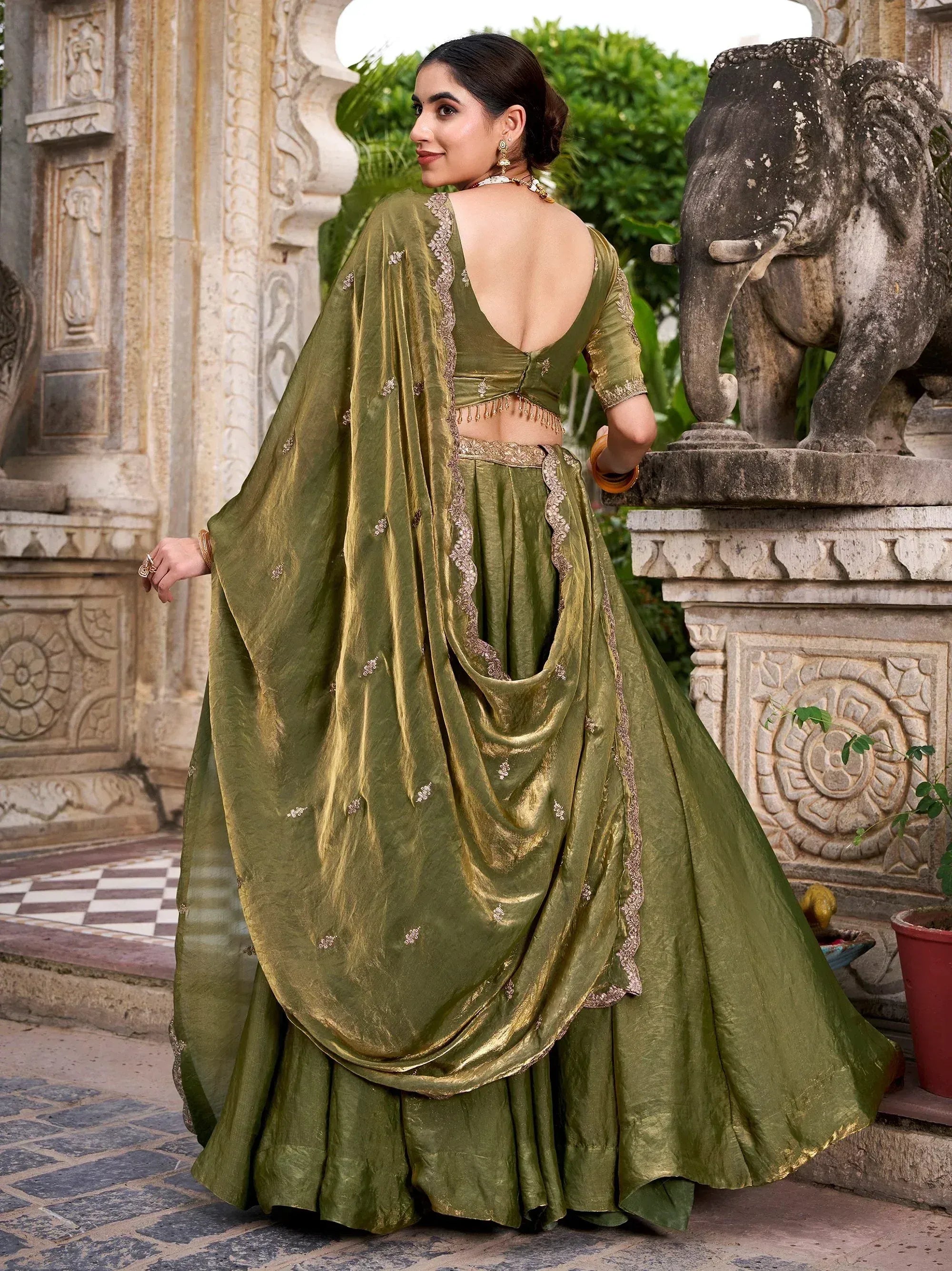 Olive green designer lehenga choli with gold embroidery, backless blouse, and dupatta, perfect for Indian ethnic occasions.