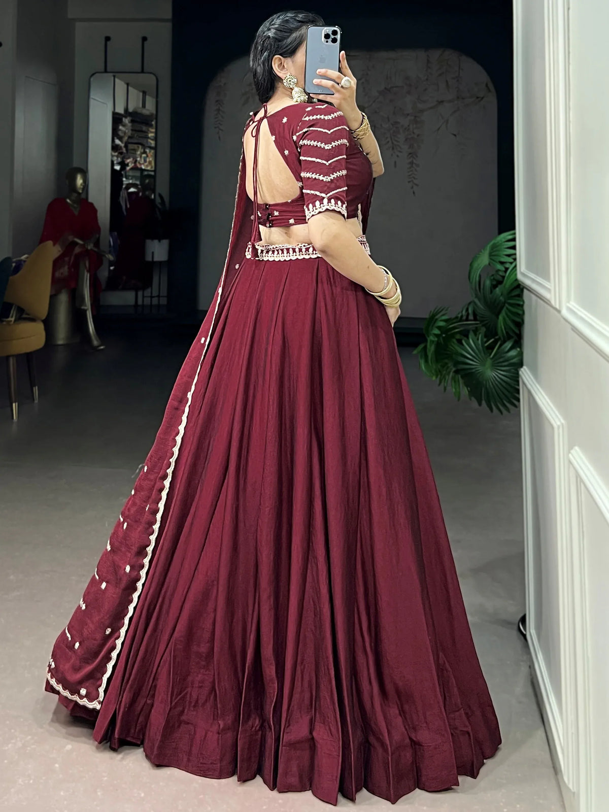Woman in a maroon designer lehenga choli with white embroidery and a matching dupatta.