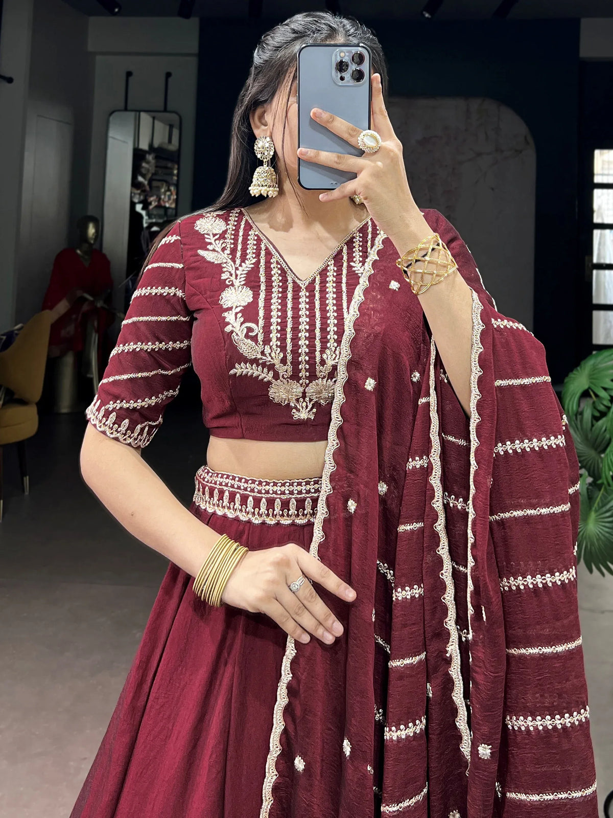 Woman wearing a maroon designer lehenga choli with gold embroidery and matching dupatta