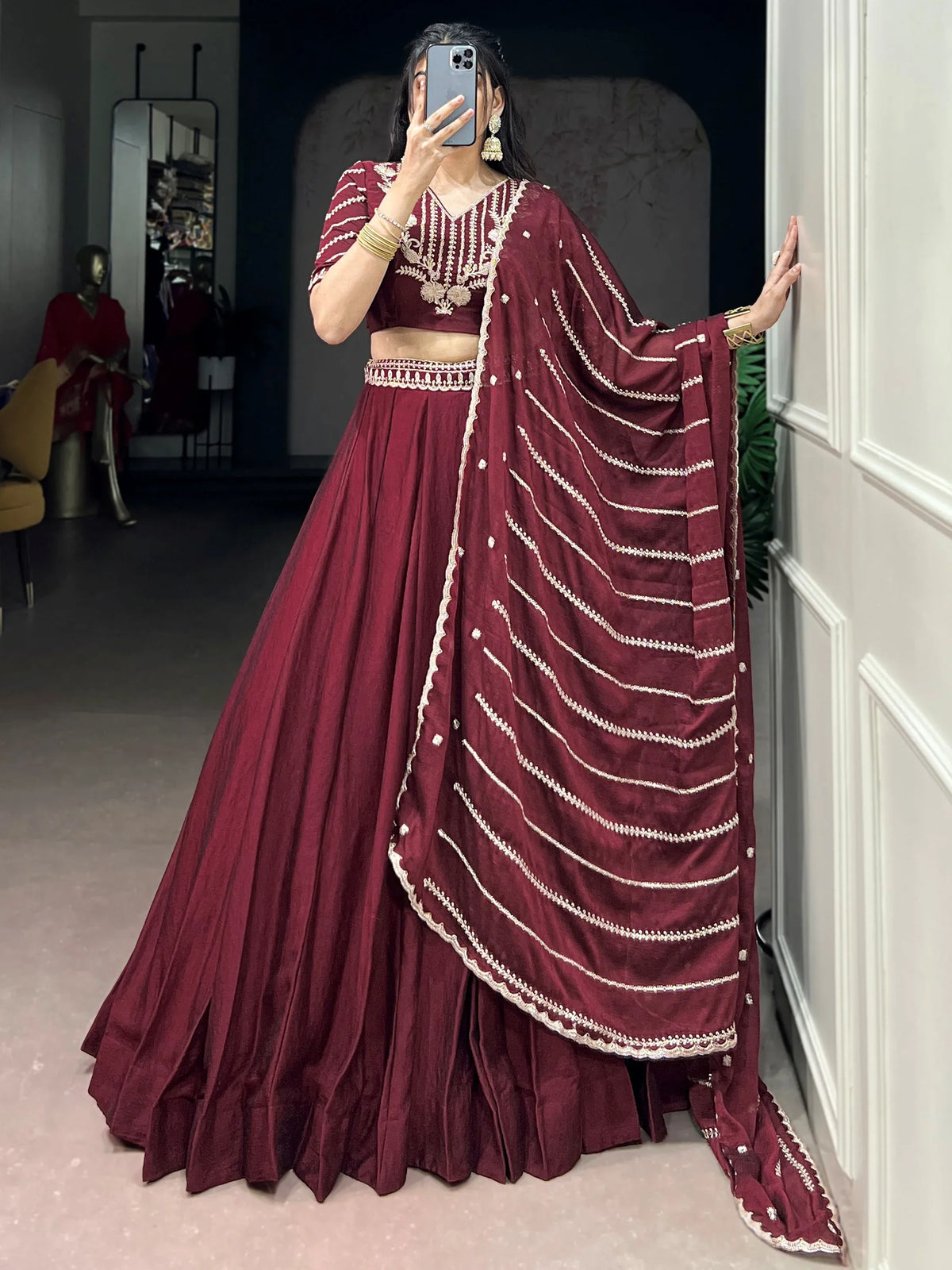 Woman wearing a maroon designer lehenga choli with white embroidery and a matching dupatta