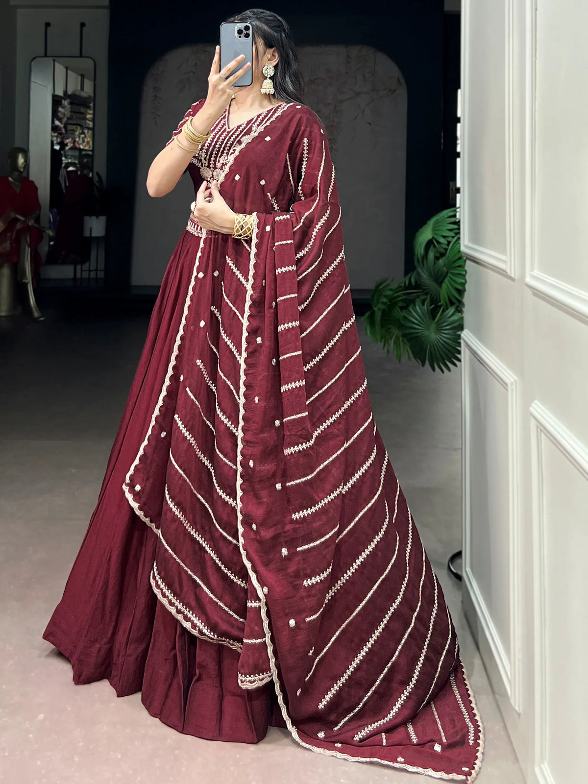 Woman wearing a maroon ethnic gown with intricate white embroidery and a matching dupatta