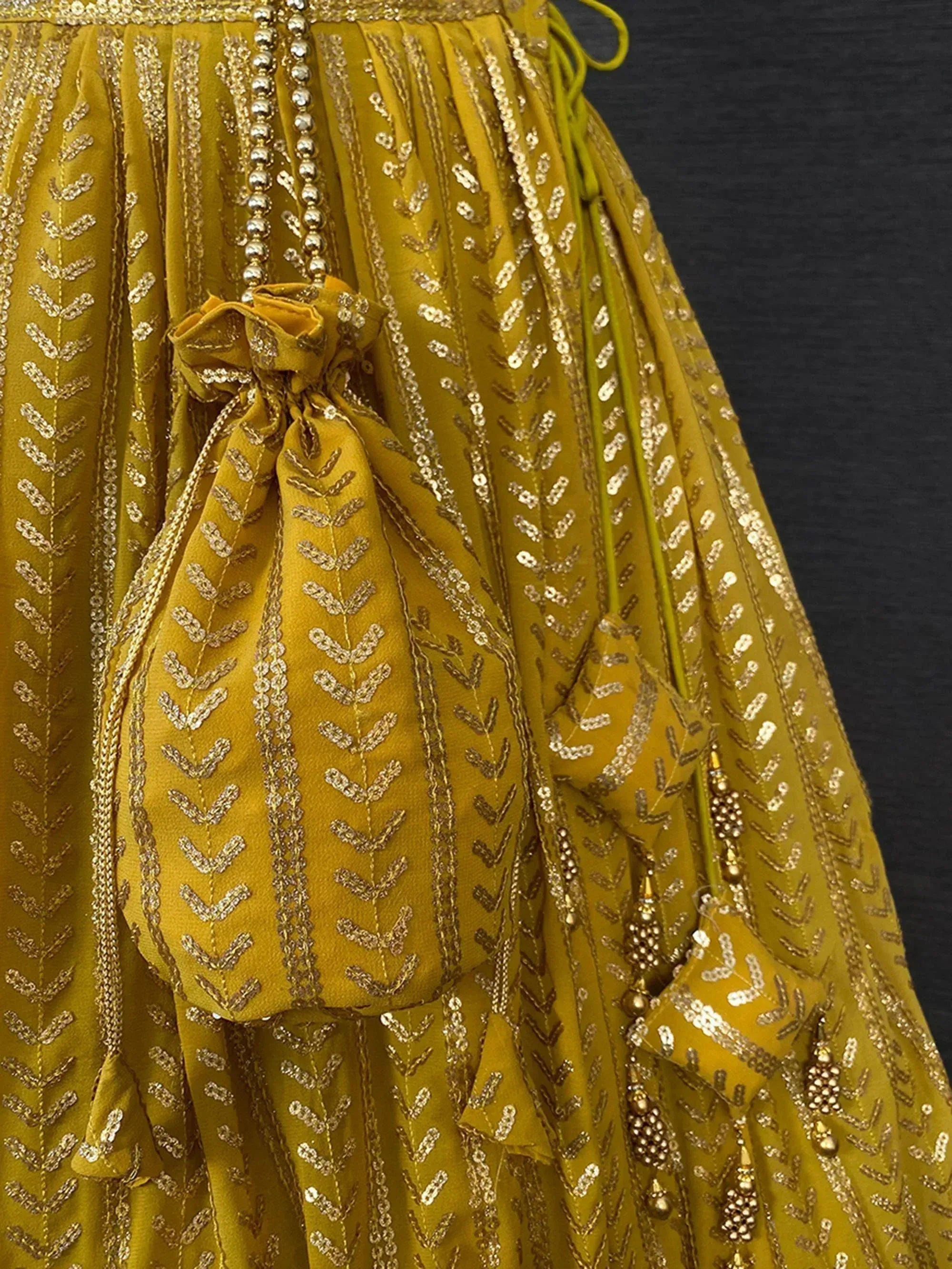 Mustard yellow ethnic gown with gold embroidery, sequins, and beaded tassels for festive occasions