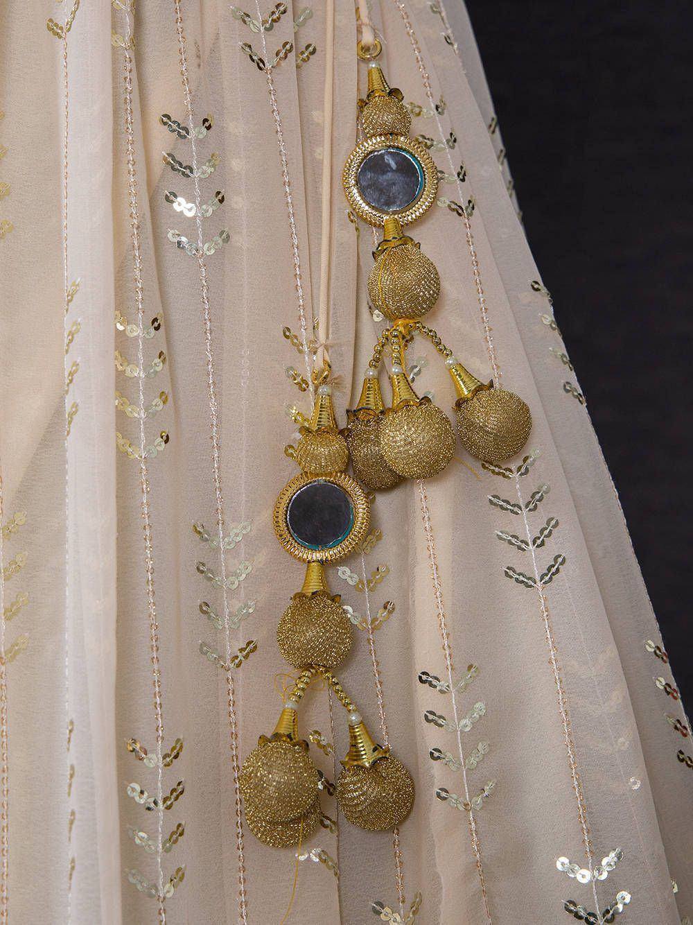 Gold mirror tassels on sheer ethnic lehenga with sequin embroidery, perfect for Indian weddings