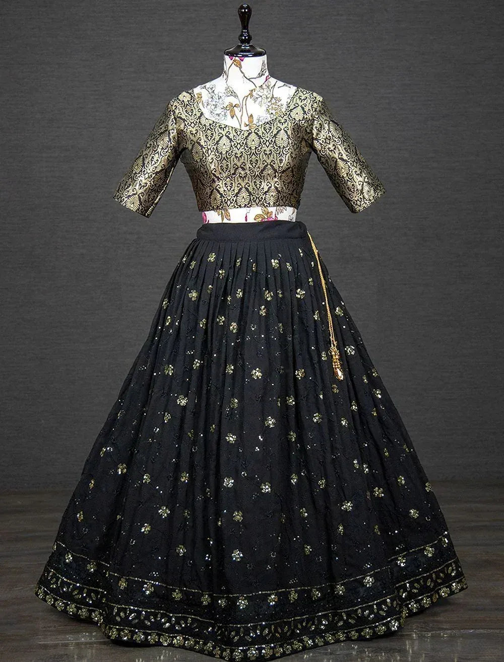 Black and gold embroidered lehenga choli with floral motifs and pleated skirt, ideal for Indian ethnic occasions