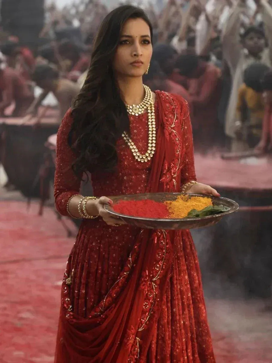 Woman in red ethnic lehenga choli holding Holi colors, festive Indian attire