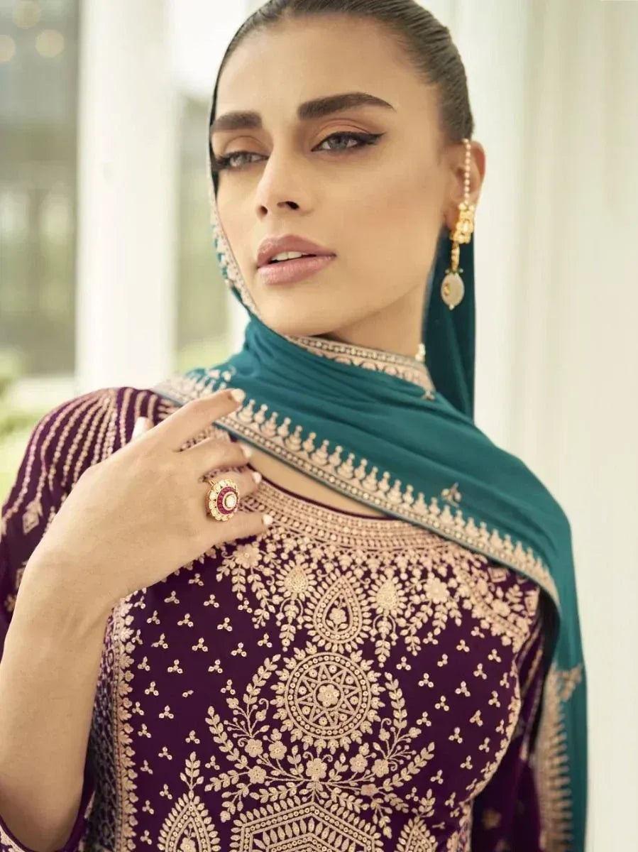 Woman in maroon embroidered ethnic gown with teal dupatta and gold jewelry