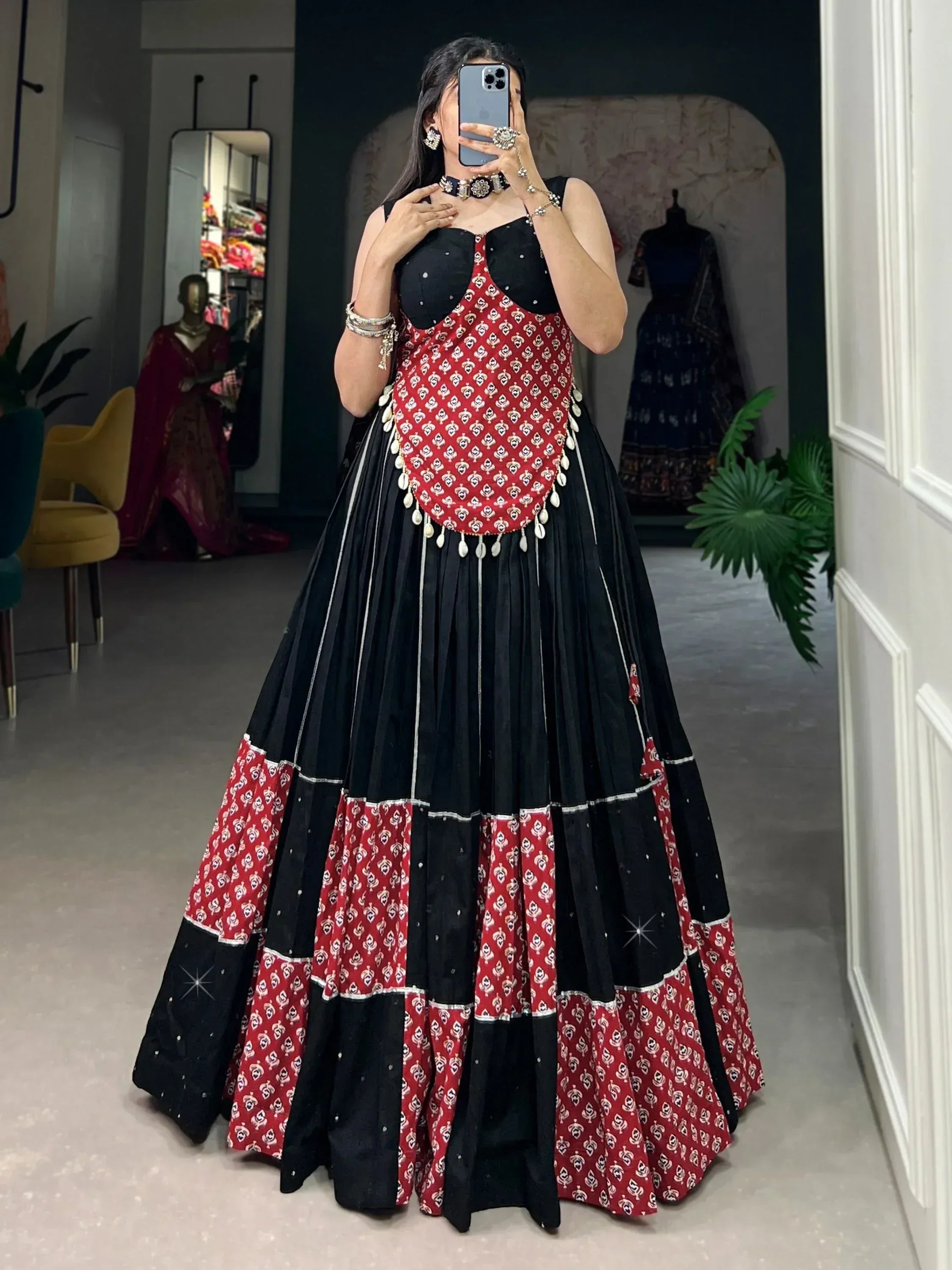 Black and red printed ethnic gown with layered skirt and embellished bodice, perfect for festive occasions.