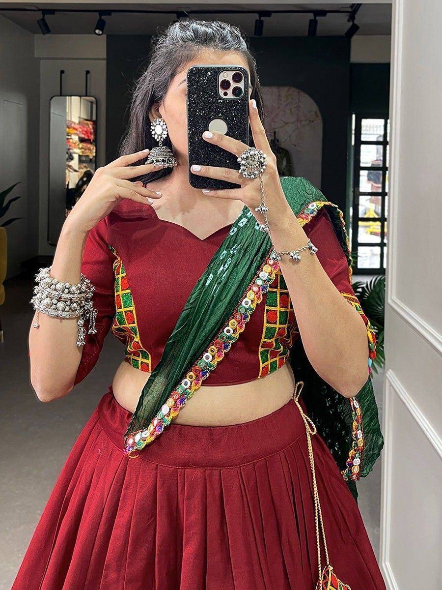 Maroon lehenga choli with green dupatta, mirror work, and traditional jewelry for ethnic wear