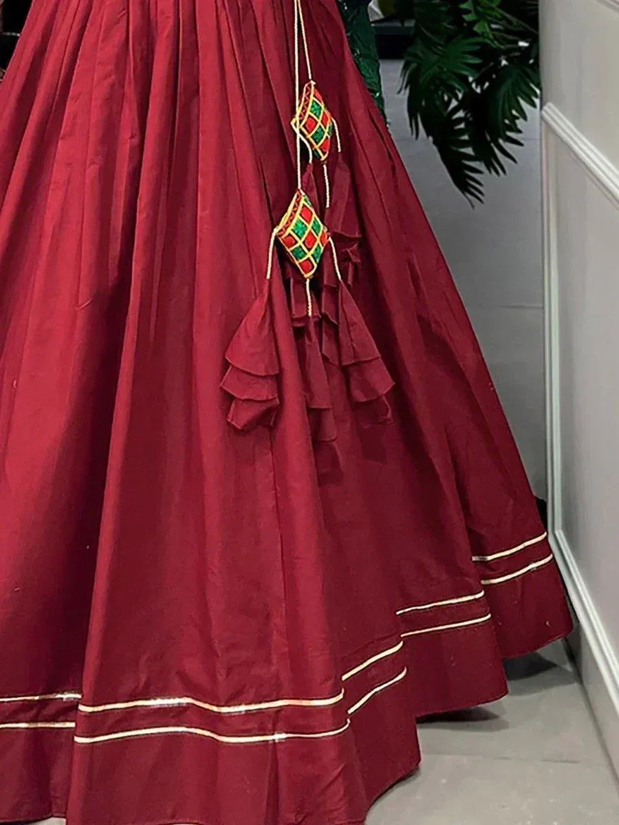 Maroon lehenga skirt with ruffles, gold trim, and embroidered tassels for Indian ethnic wear