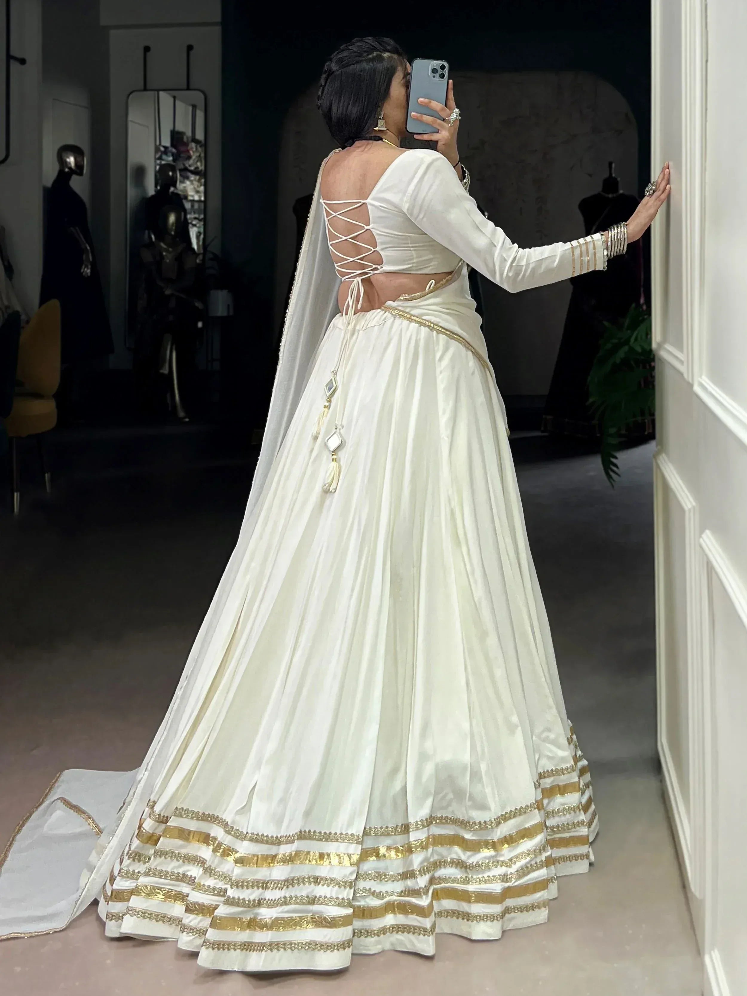 White designer lehenga choli with gold trim, back lace-up blouse, and dupatta, perfect for Indian ethnic wear.
