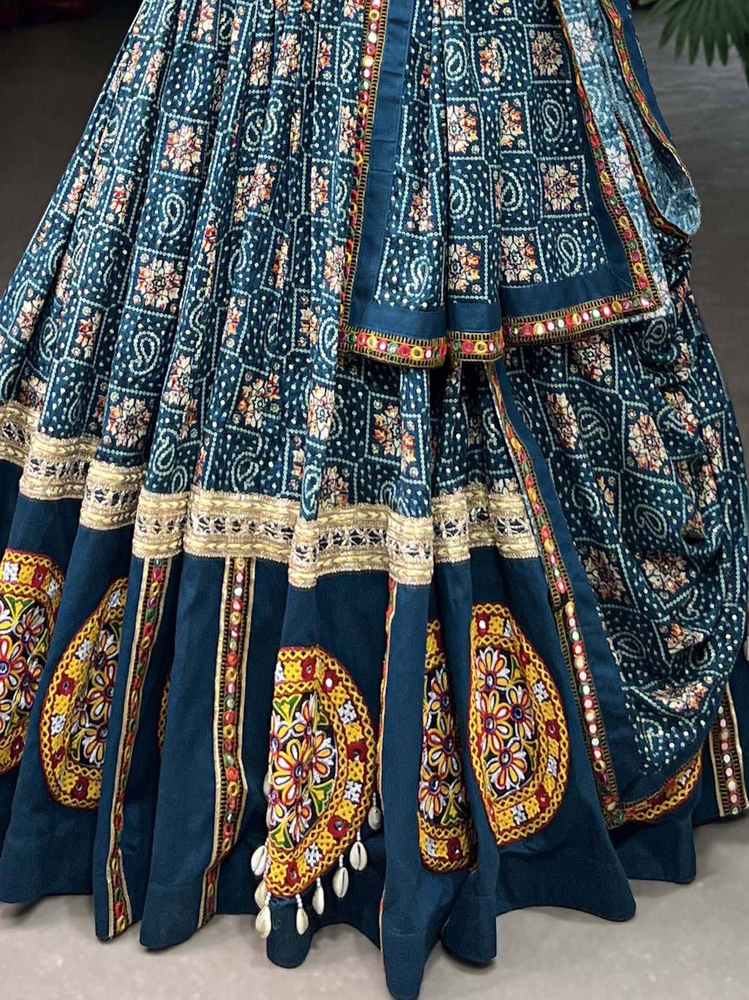 Teal ethnic lehenga with intricate floral embroidery, mirror work, and shell tassels for Indian weddings