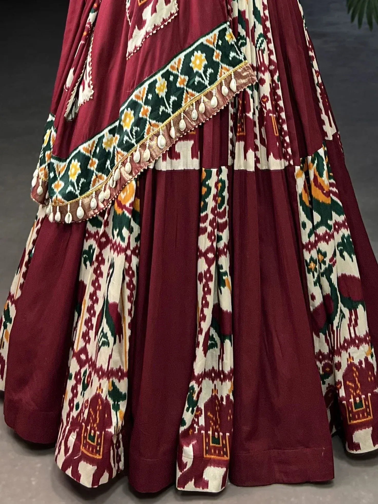 Maroon and white ethnic lehenga with ikat print, floral border, and tassel detailing