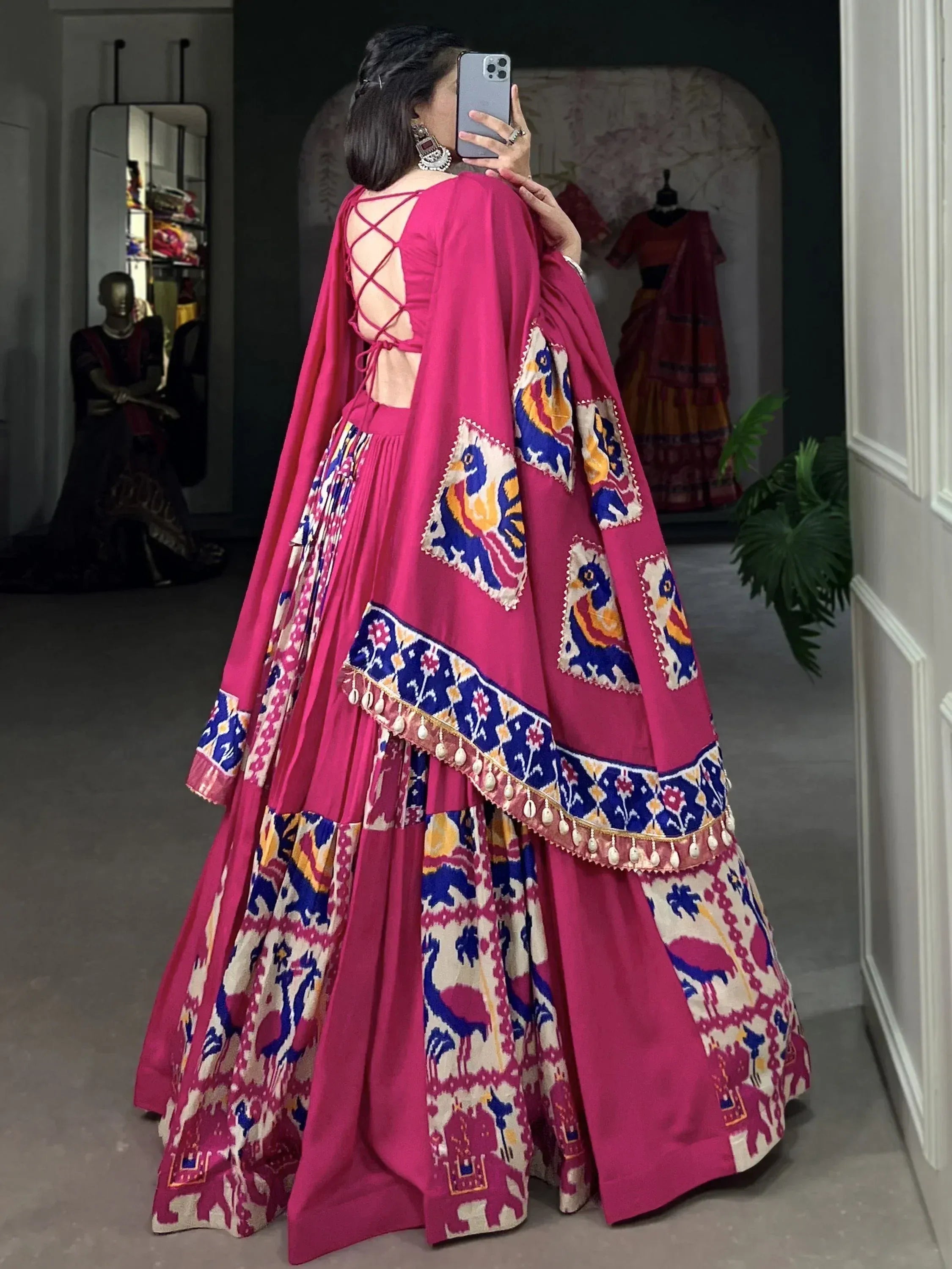 Pink ethnic lehenga choli with peacock print and crisscross back, perfect for Indian weddings or festive occasions.