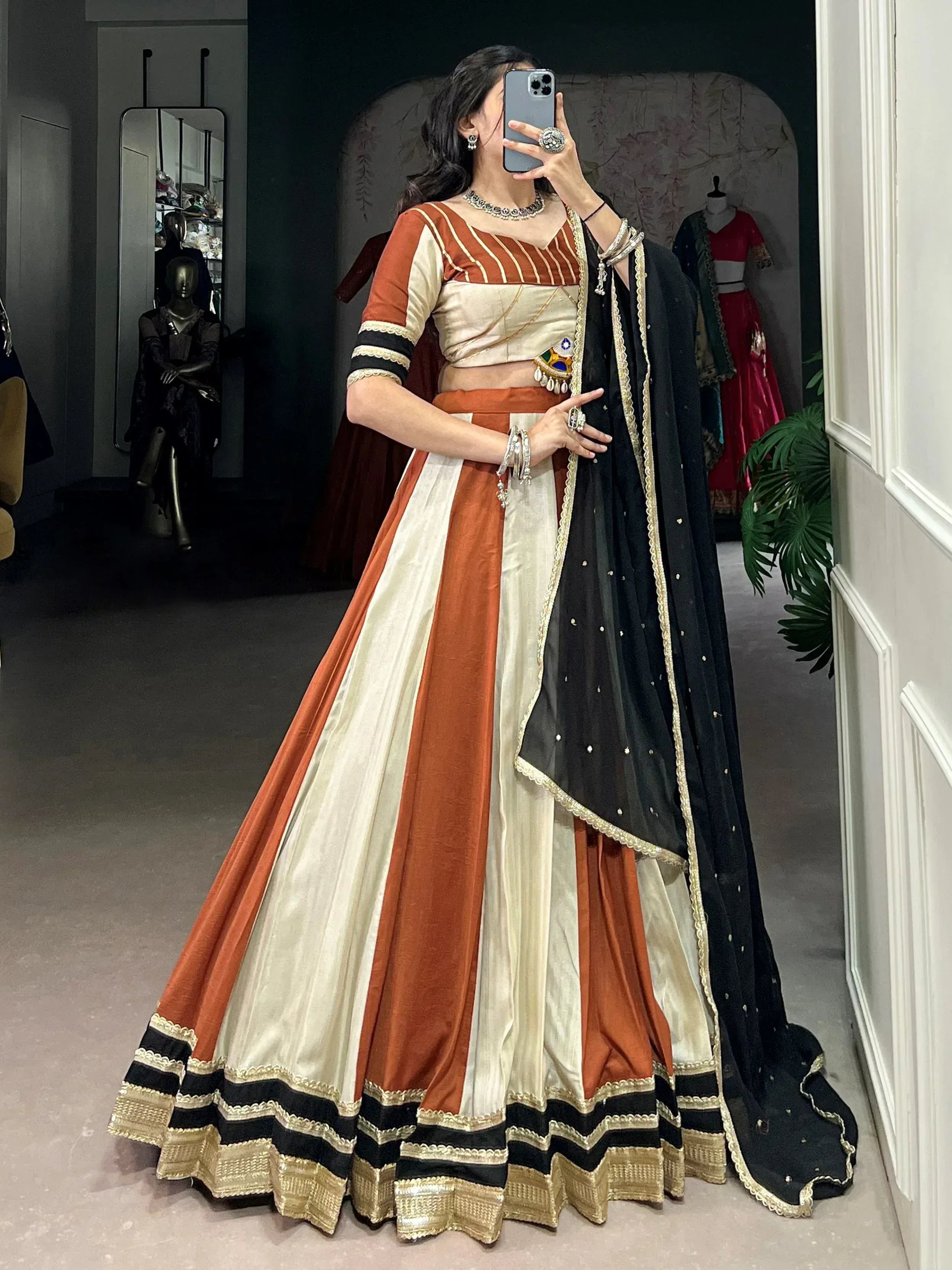 Woman in orange and cream striped lehenga choli with black dupatta, ethnic Indian wear