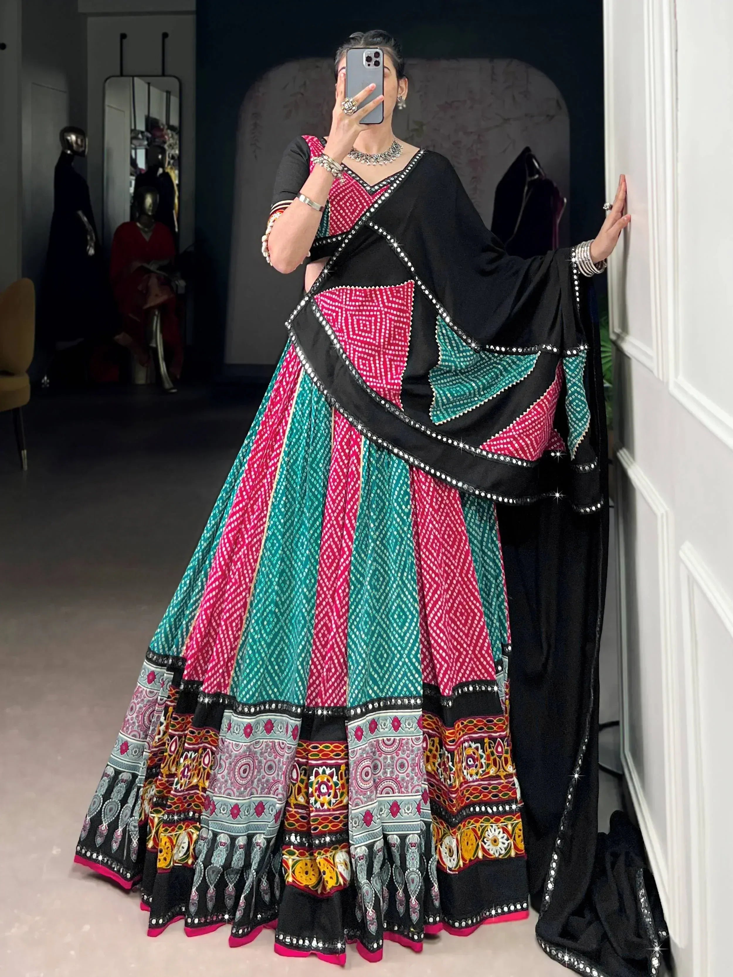 Black, pink, and teal ethnic lehenga choli with mirror work and geometric patterns, perfect for festive occasions.