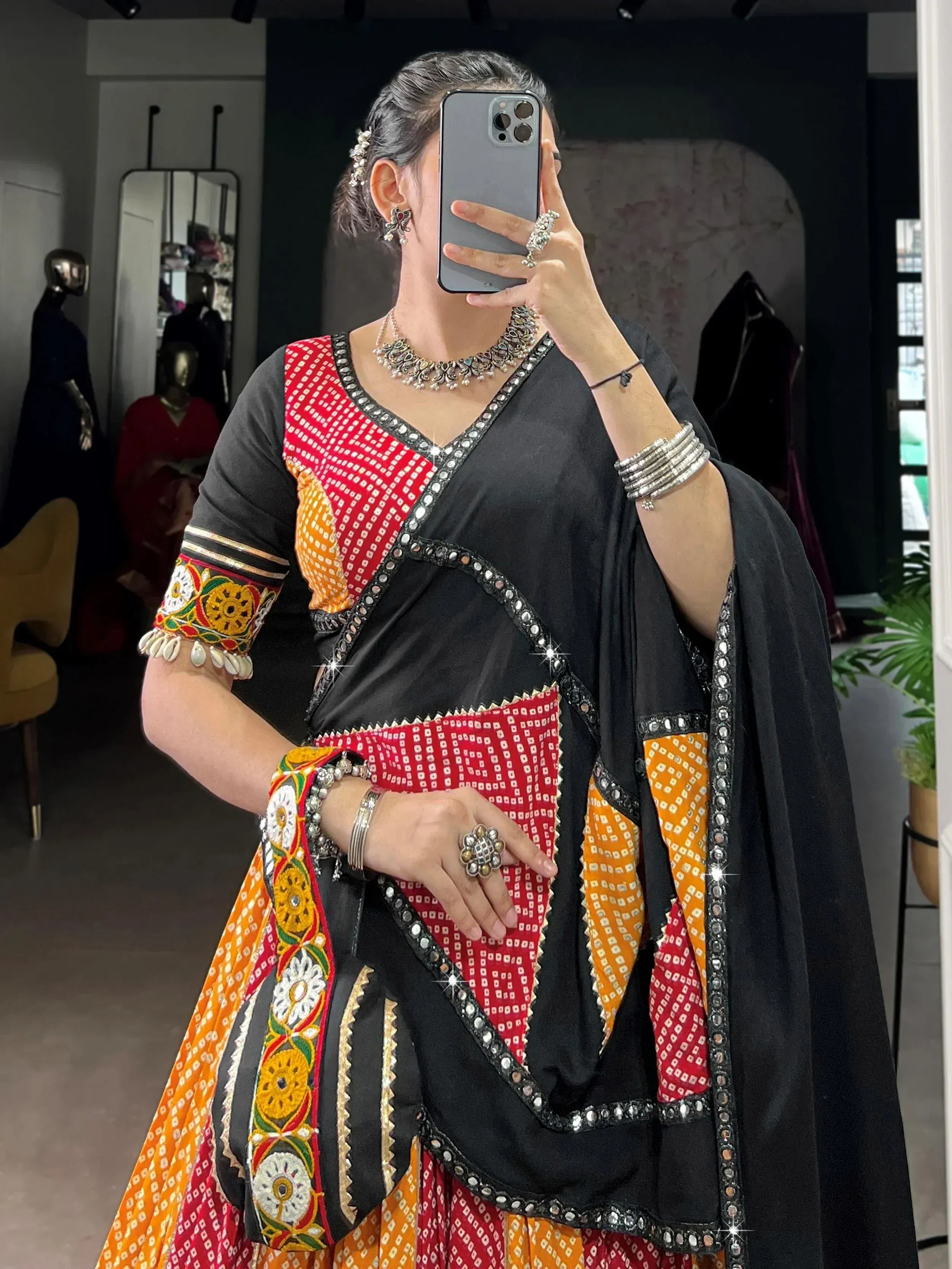 Black, red, and orange embroidered ethnic lehenga choli with mirror work and traditional jewelry