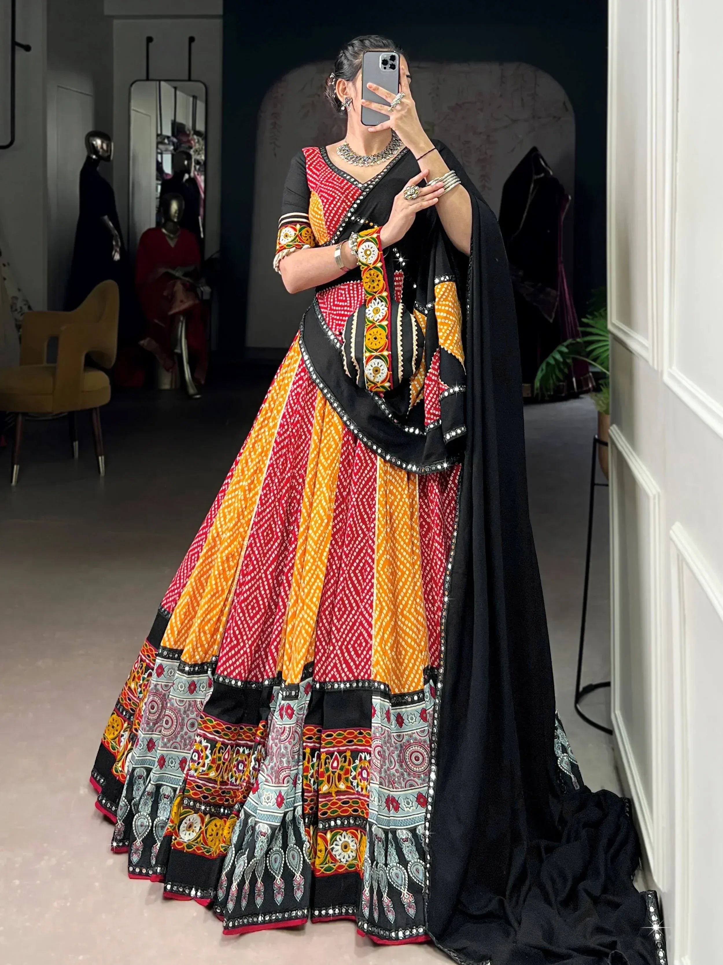 Woman in vibrant red and orange printed lehenga choli with black dupatta, ethnic Indian wear