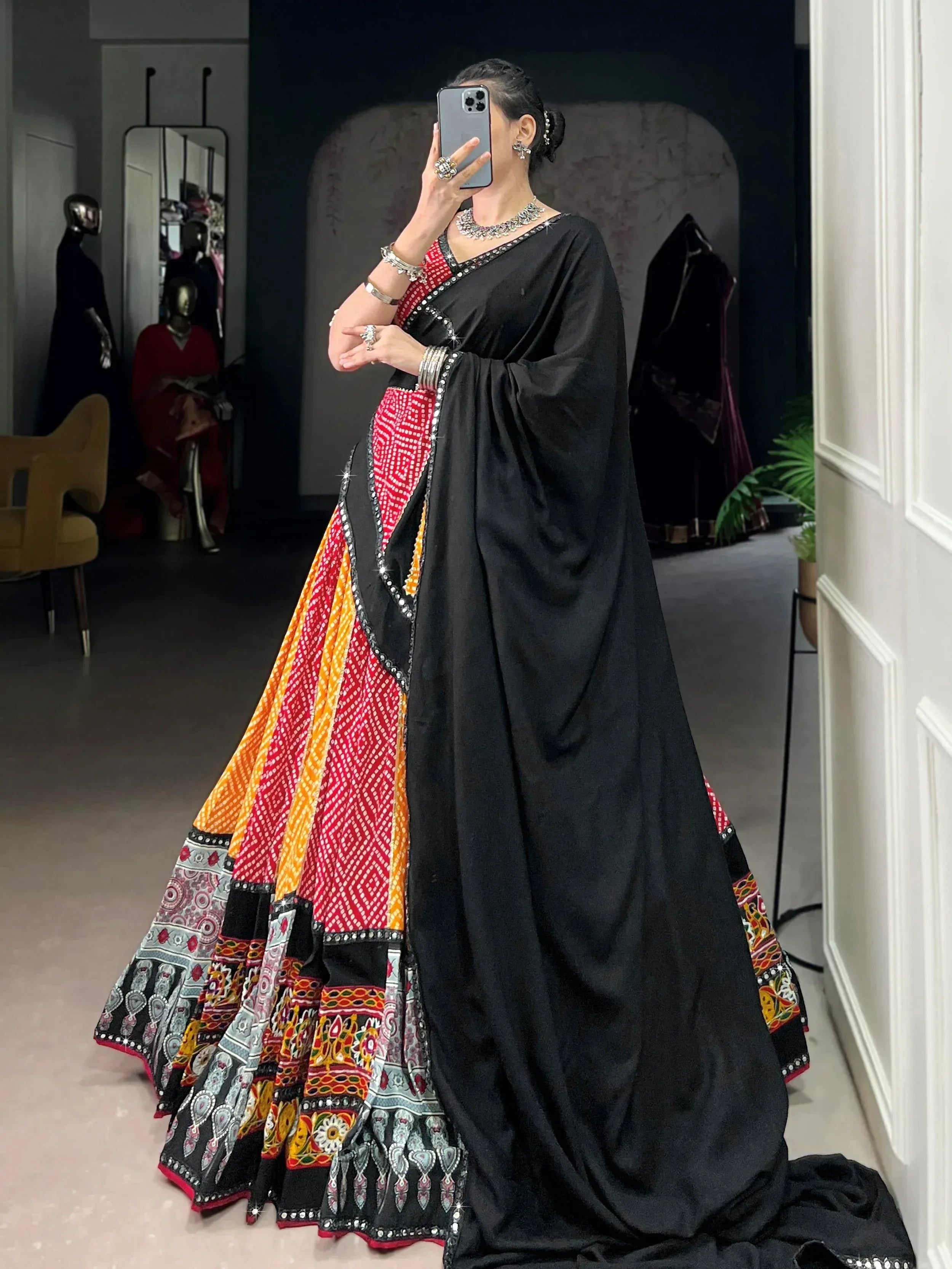 Woman in black and red embroidered lehenga choli with mirror work, perfect for Indian ethnic wear occasions.