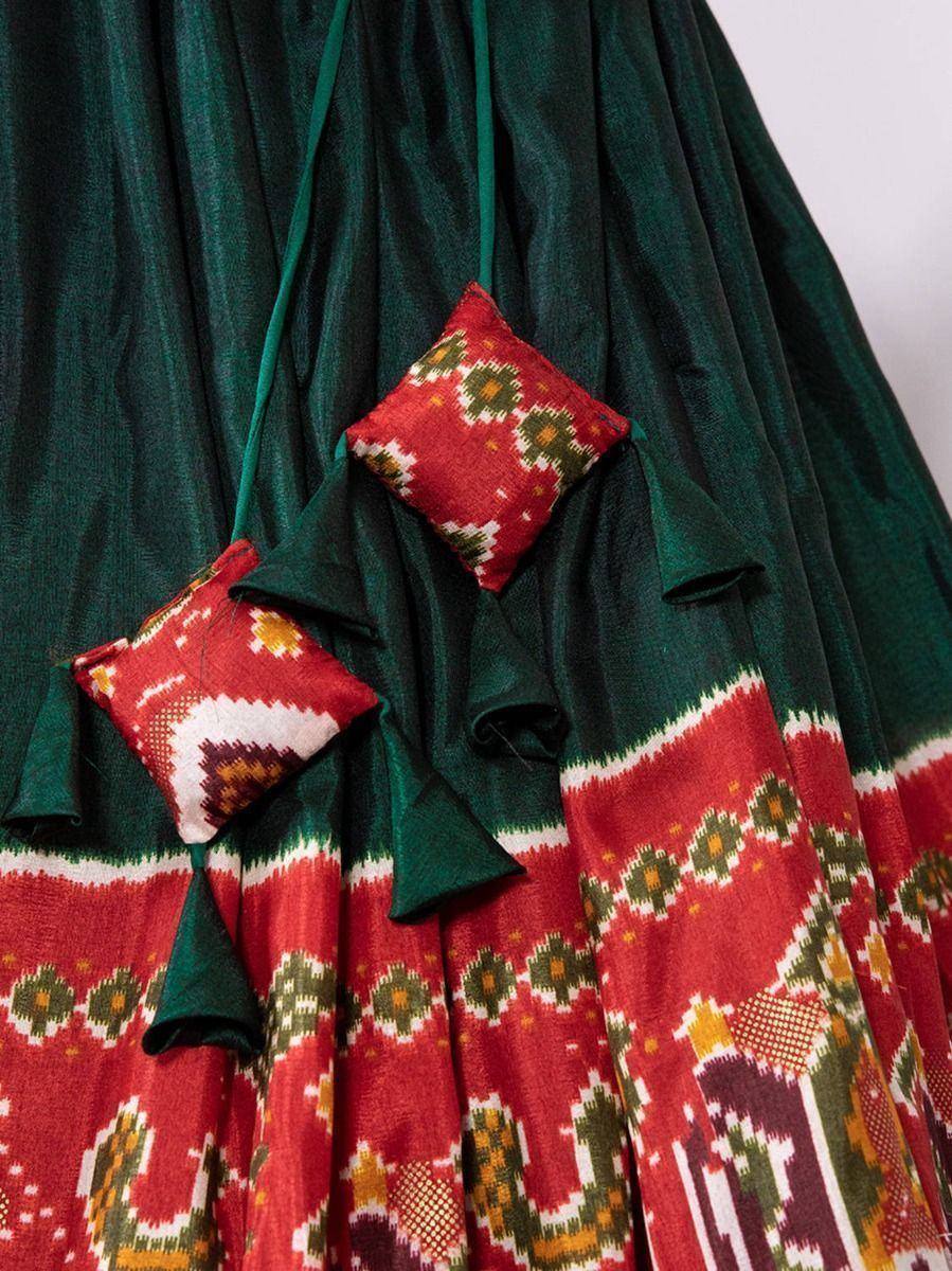 Green and red ethnic printed lehenga with decorative cushion accents, perfect for festive occasions.