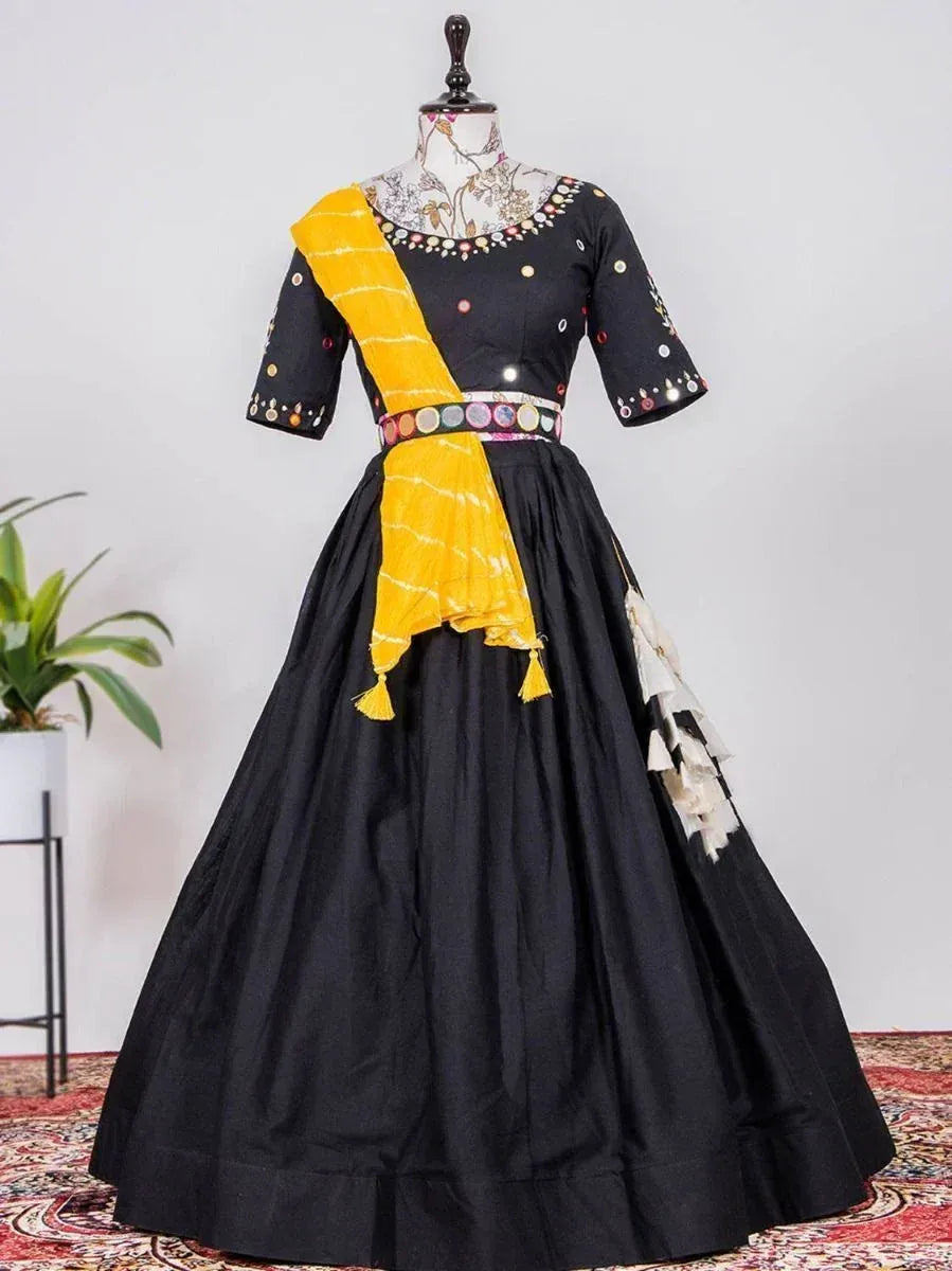 Black ethnic gown with yellow dupatta, mirror work, and tassels for festive occasions