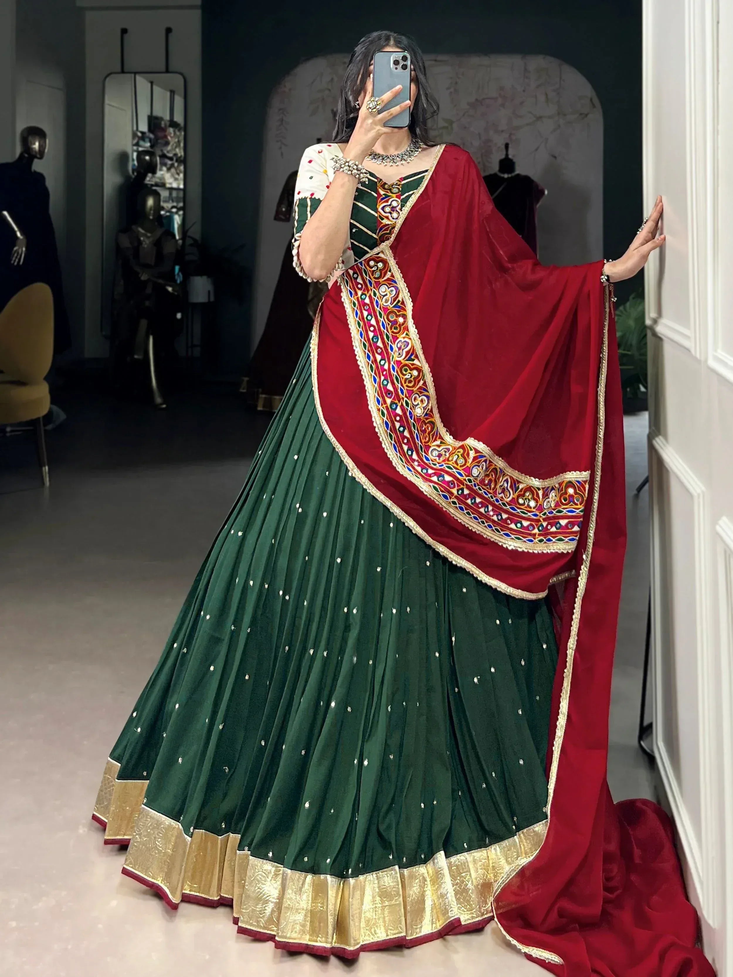 Green and red embroidered lehenga choli with mirror work and gold border, perfect for Indian ethnic occasions.