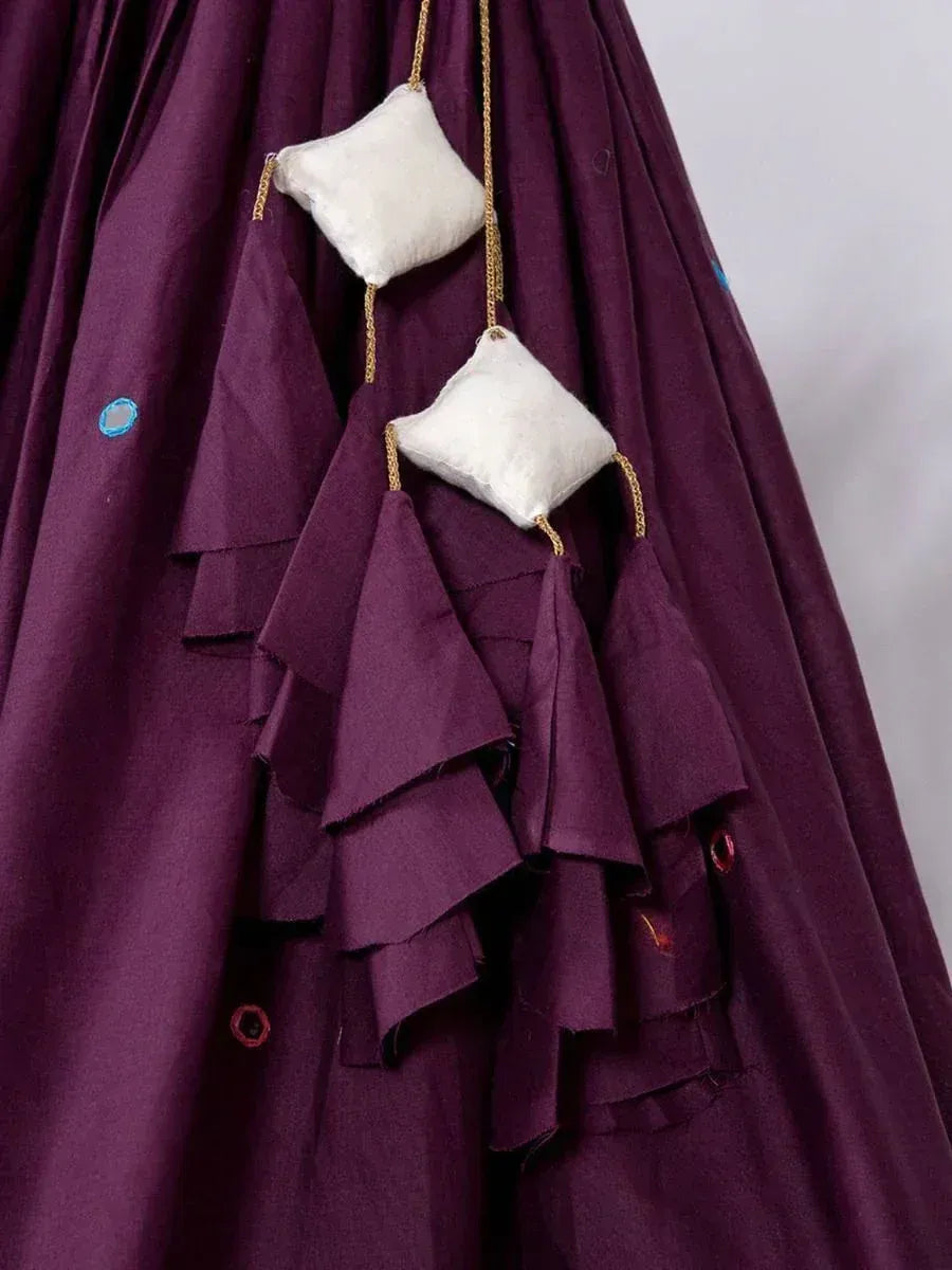 Purple ethnic gown with ruffled layers and decorative white pom-poms, perfect for Indian festive wear.