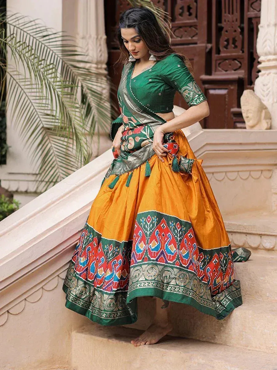 Woman in vibrant green and orange ethnic lehenga choli with peacock print, standing on stone steps
