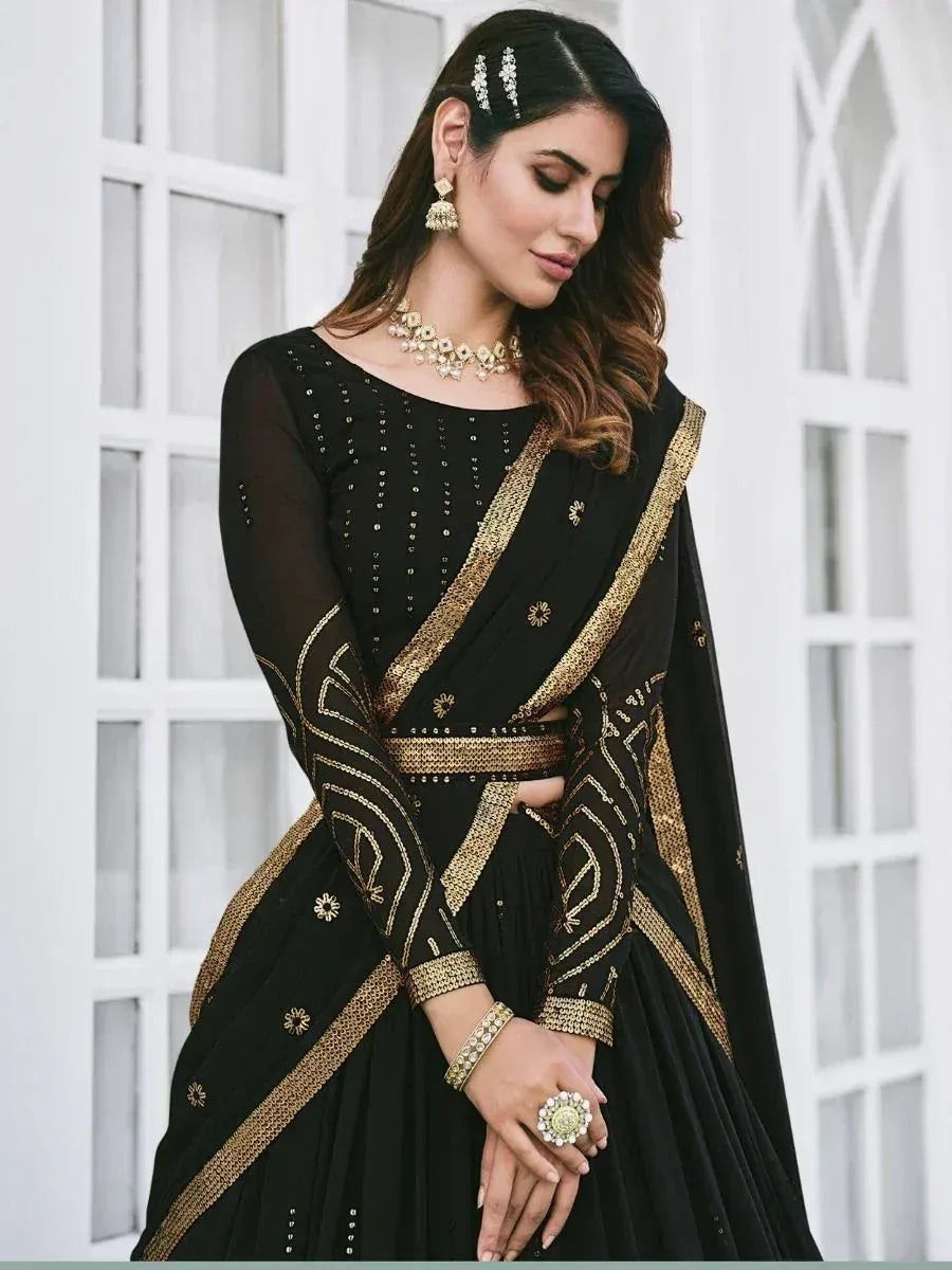 Black and gold embroidered lehenga choli with sheer sleeves and traditional jewelry