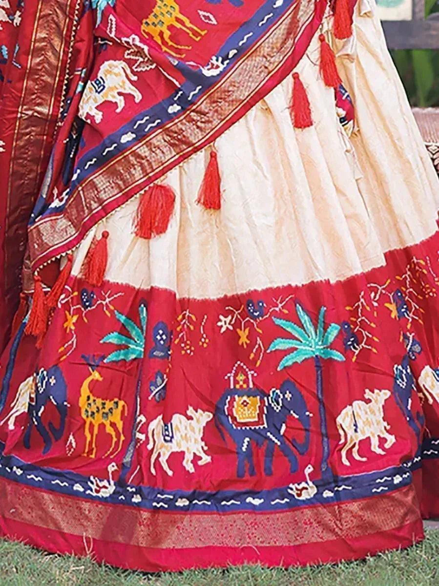 Red and cream ethnic lehenga with elephant, deer, and palm tree embroidery, tassels, and border details