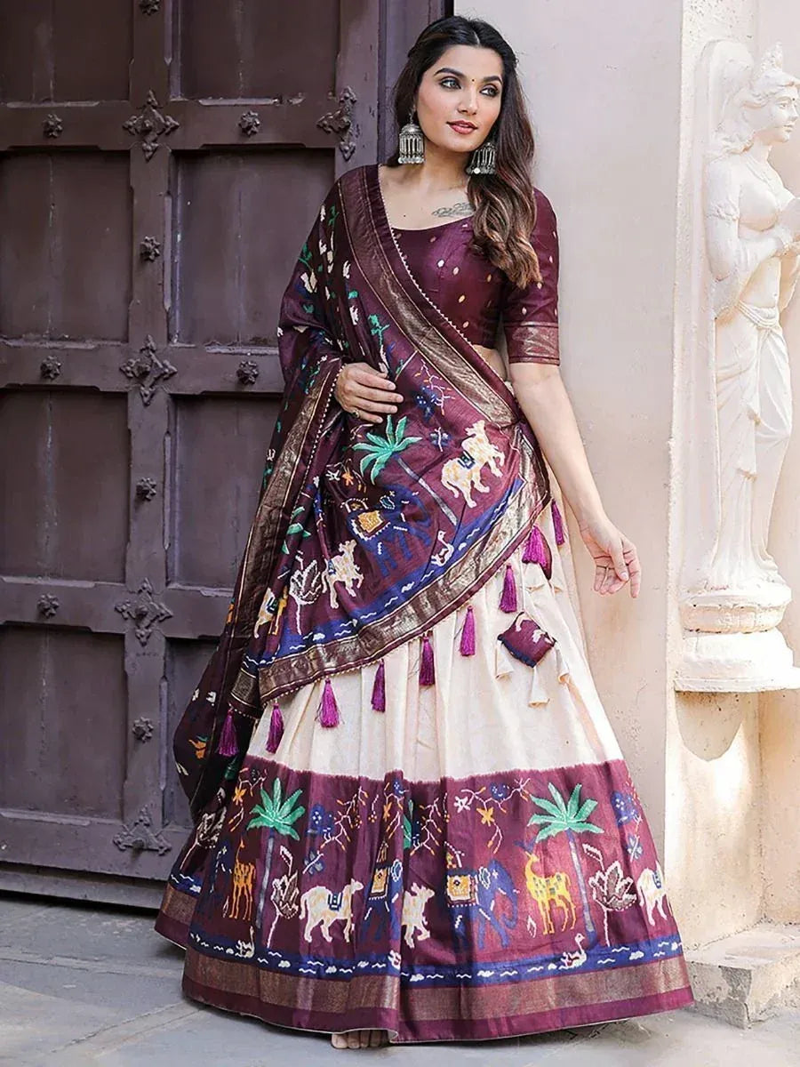 Woman in maroon and cream printed lehenga choli with elephant and palm motifs, ethnic Indian wear
