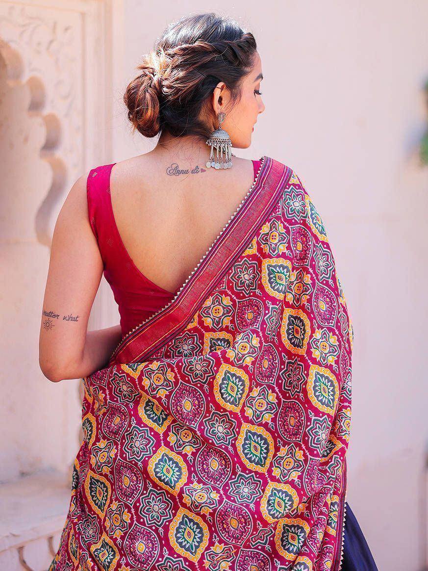 Woman in vibrant printed saree with floral motifs, backless blouse, and jhumka earrings