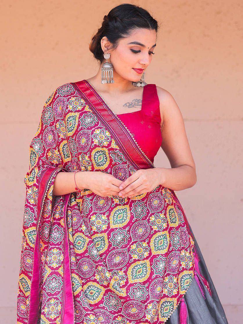 Woman in vibrant pink printed lehenga choli with floral motifs, ethnic Indian wear