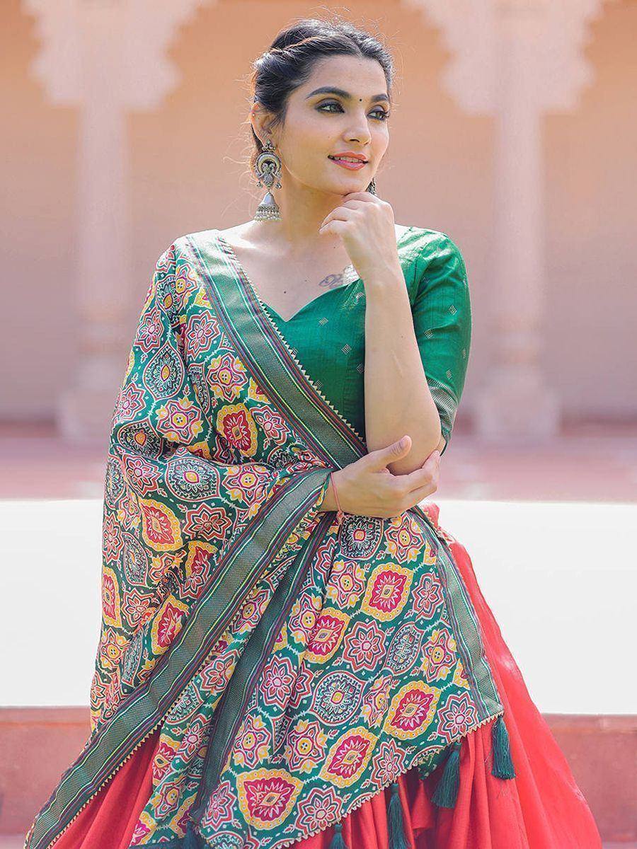 Woman in vibrant green and red printed saree with floral motifs, styled with ethnic jewelry for festive occasions