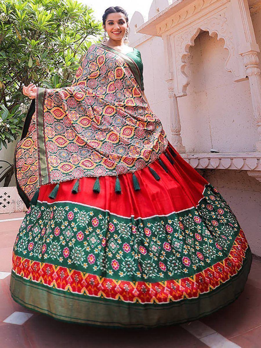 Woman in vibrant red and green ethnic lehenga choli with floral print and tassels, perfect for Indian festivals