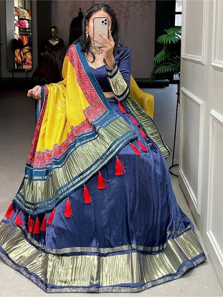 Blue velvet lehenga choli with yellow dupatta, red tassels, and gold trim for Indian ethnic wear